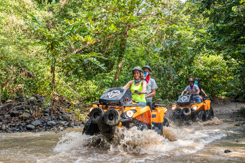 A couple of ATVs splash through knee deep water