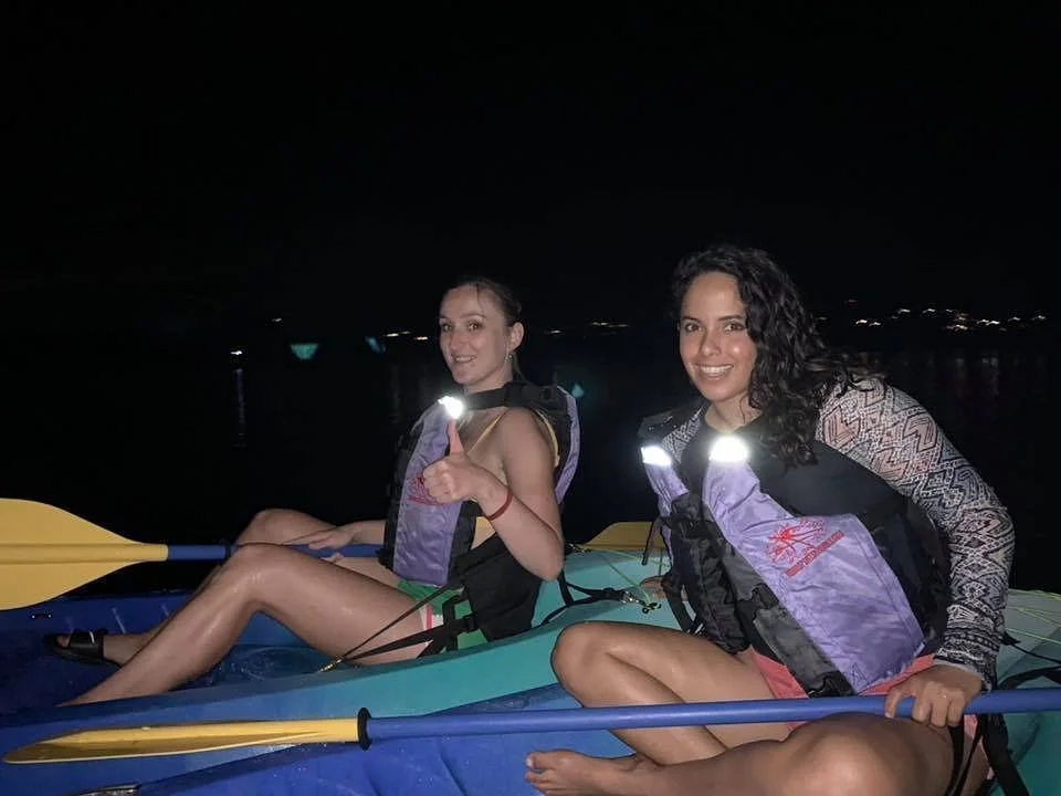 Two kayakers smile and give a thumbs up for the camera