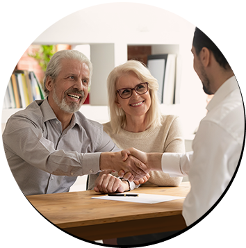 A couple shaking hands across a desk with an advisor