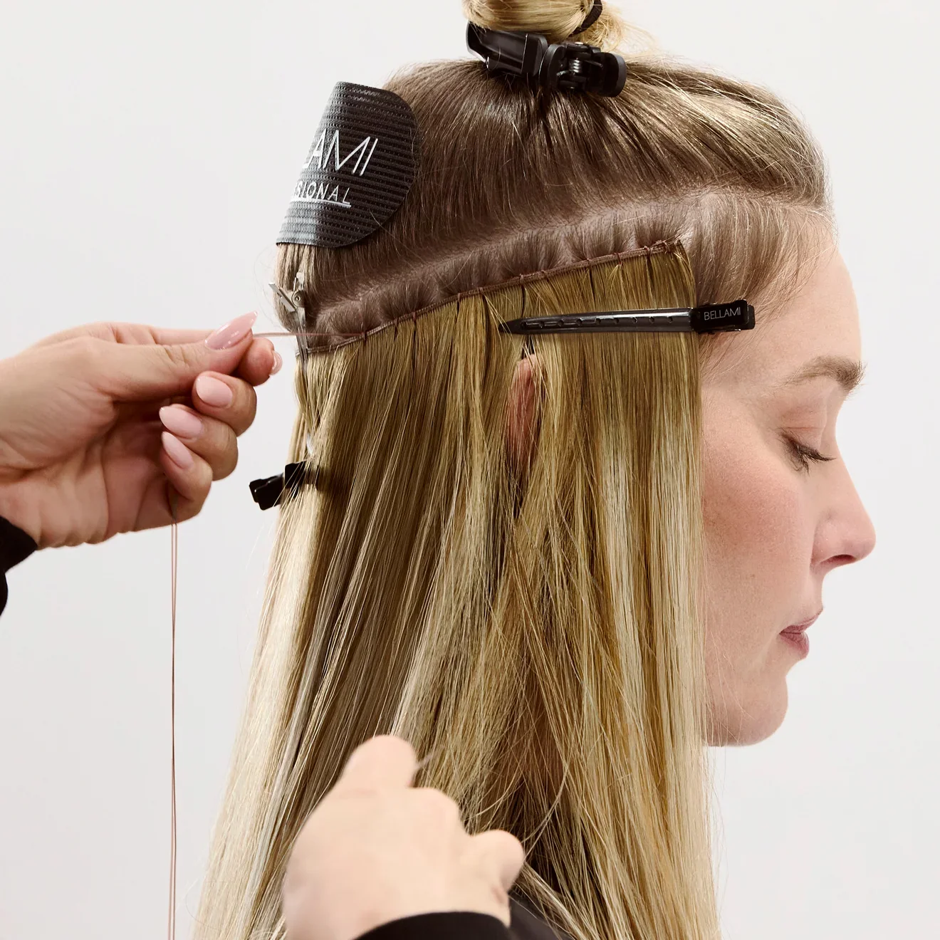 A stylist installing BELLAMI weft extensions