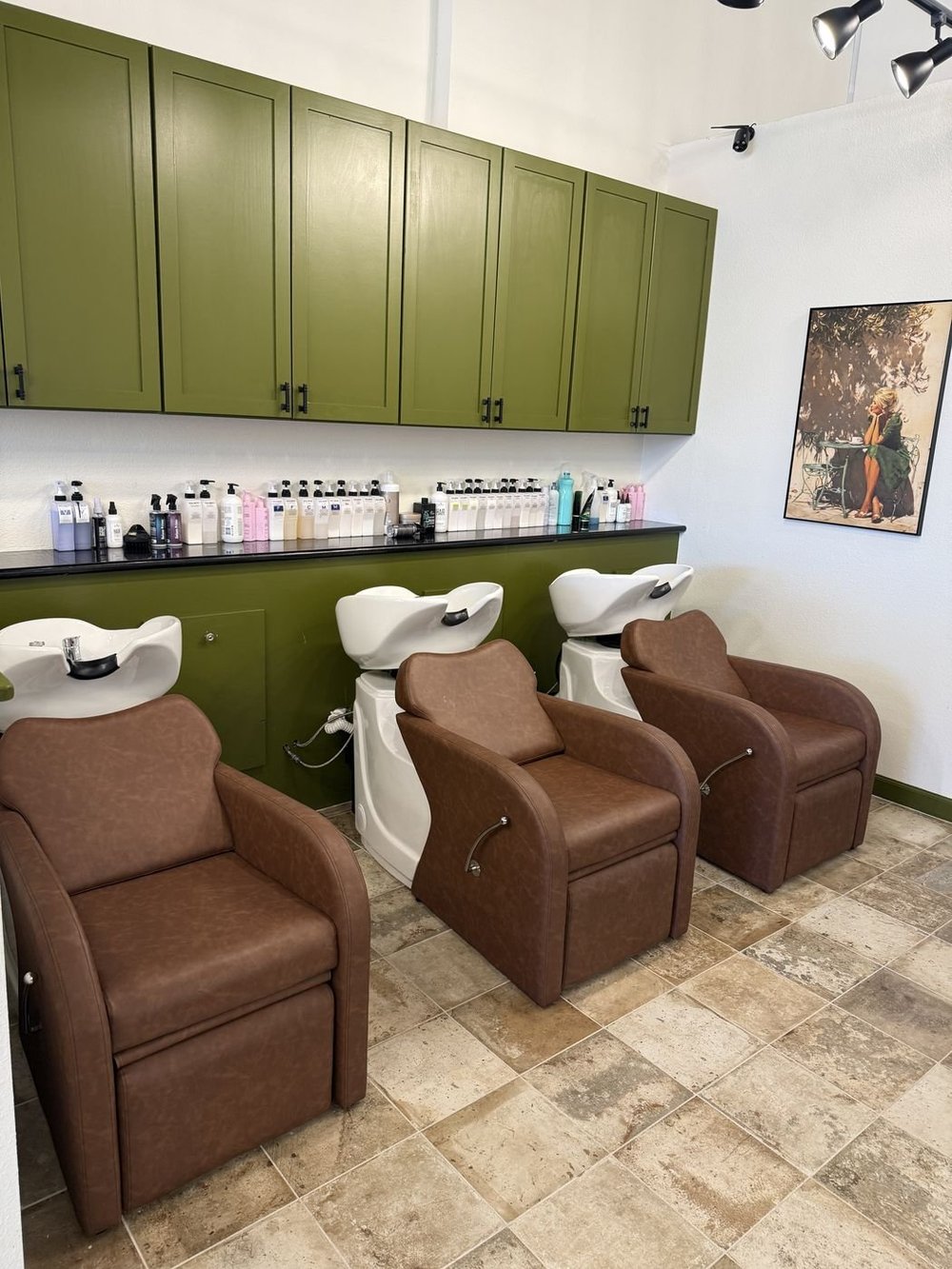 Leather shampoo chairs beneath olive green cabinetry at the Alamo Heights salon