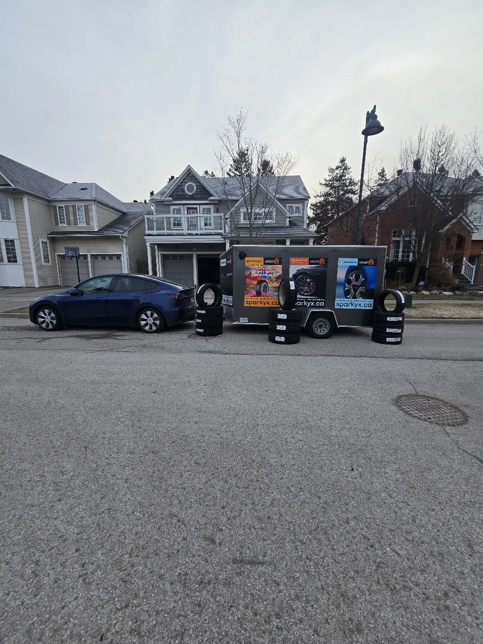 Sparky X Mobile Tire Shop service trailer and stacks of new tires around it.