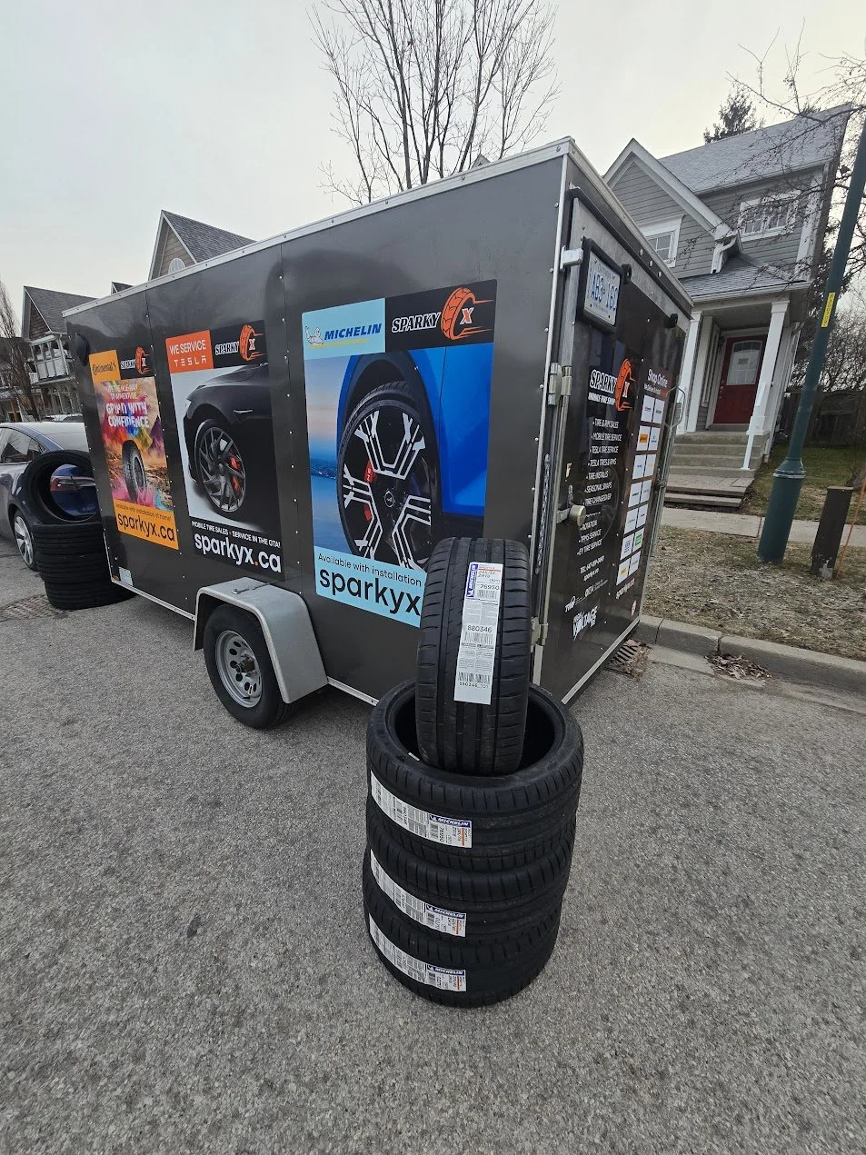 Precision mobile tire shop sales and service - stack of Michelin tires near Sparky X service trailer