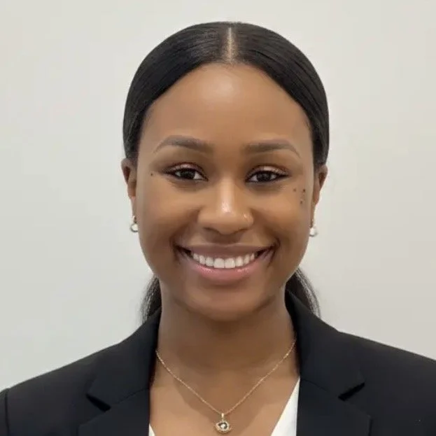Shaniyah Wrighton smiling in a black blazer against a light background.
