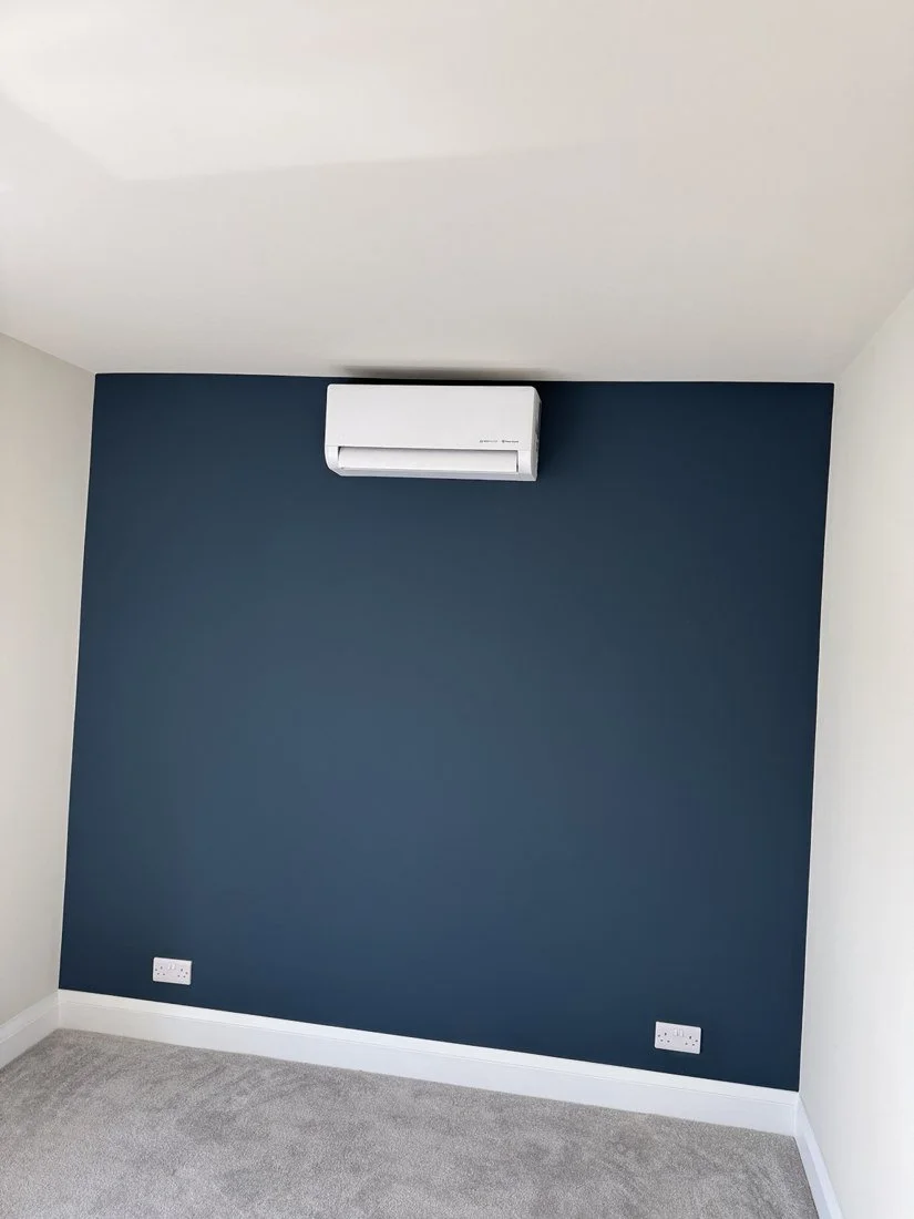 White wall-mounted air conditioning unit on a blue feature wall