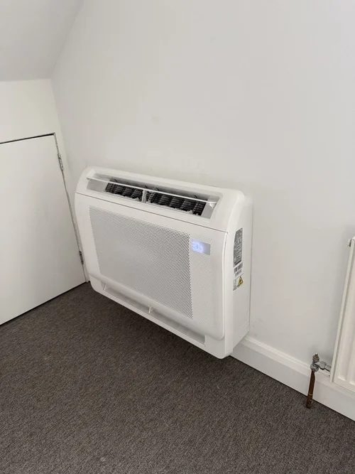 Floor-mounted air conditioning console beneath a sloping ceiling