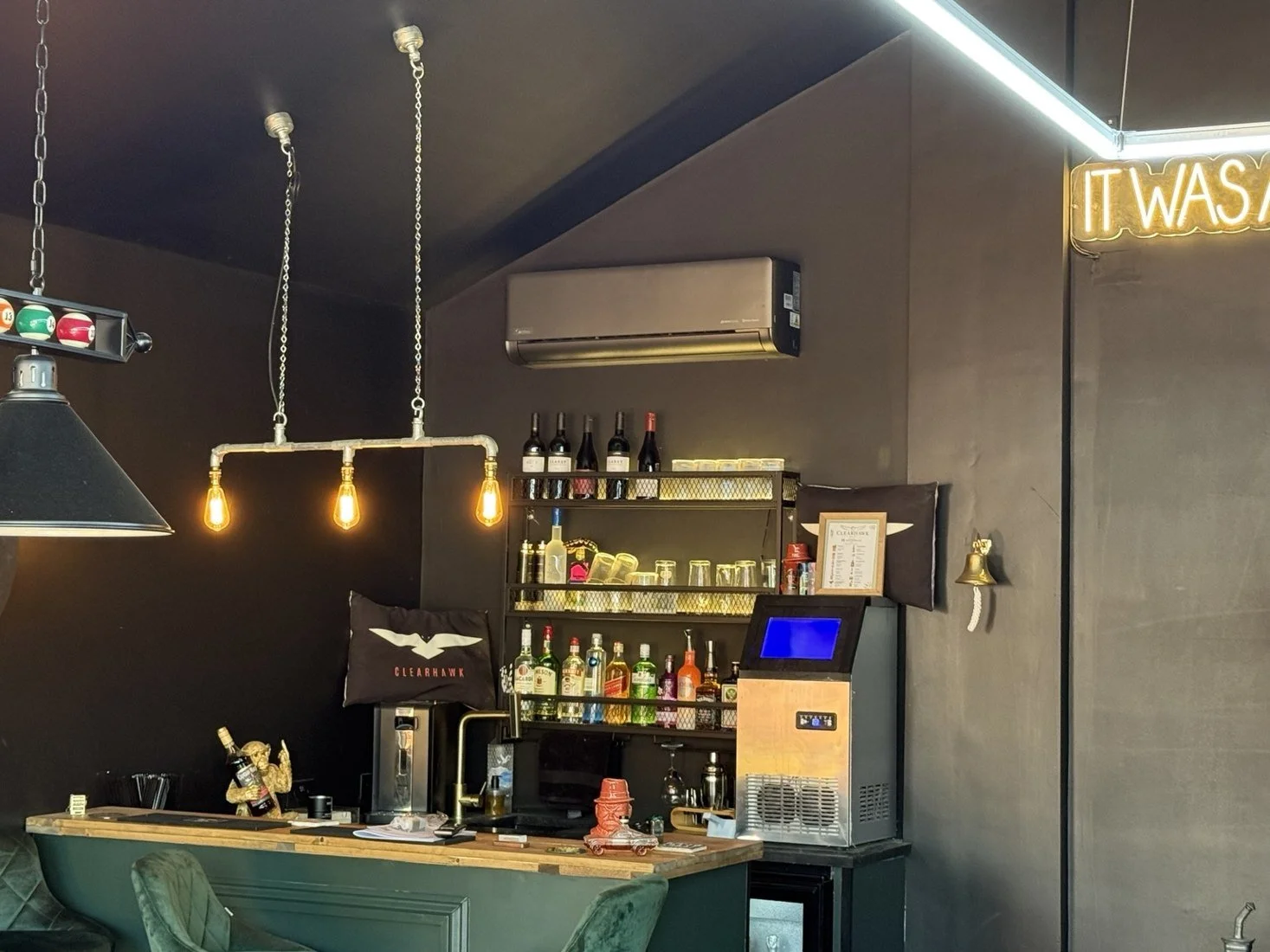 Dark wall-mounted air conditioning unit above a bar area