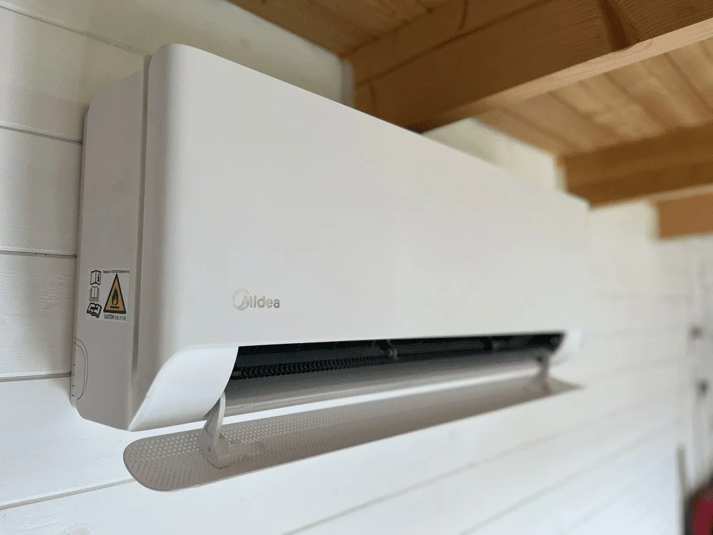 White wall-mounted indoor unit beneath a timber ceiling