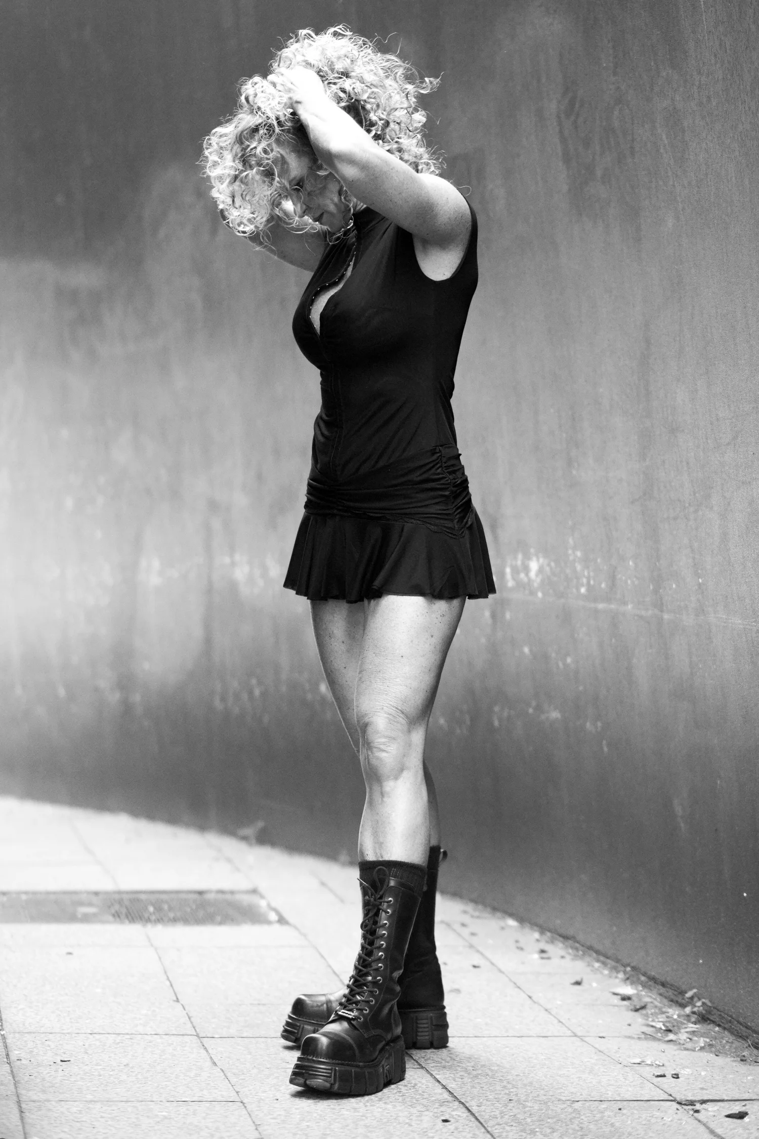Chrisanna standing in boots, one arm over her head, curls falling