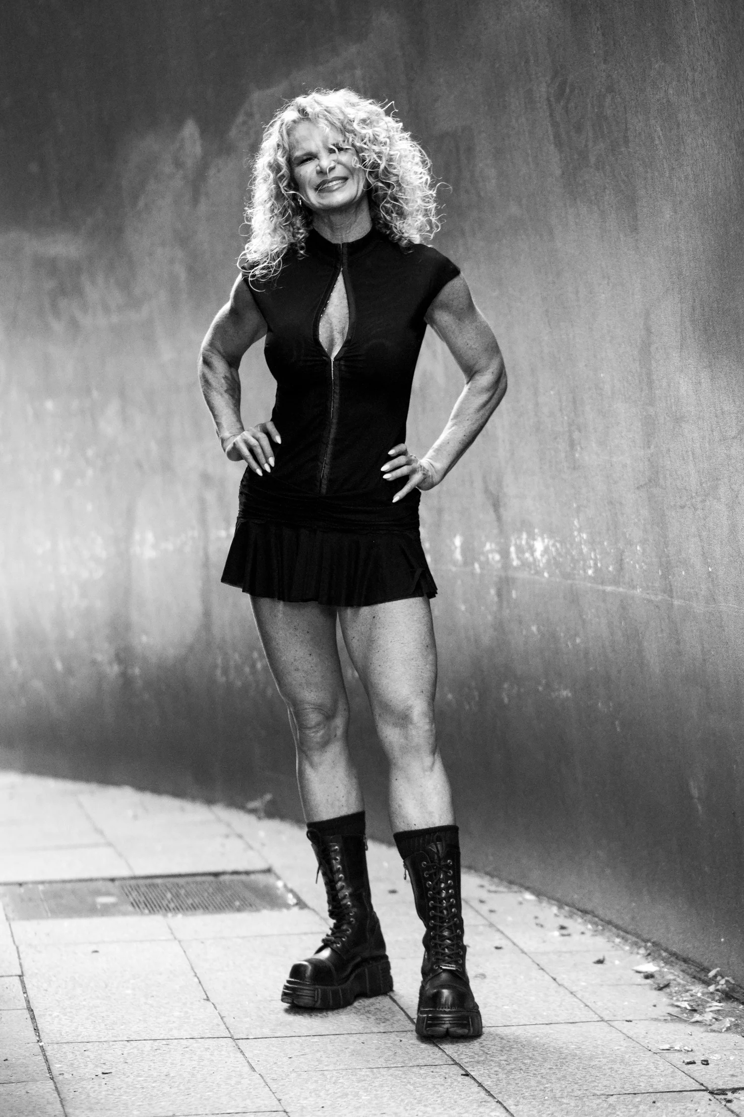 Chrisanna smiling, hands on hips, in heavy boots between steel walls