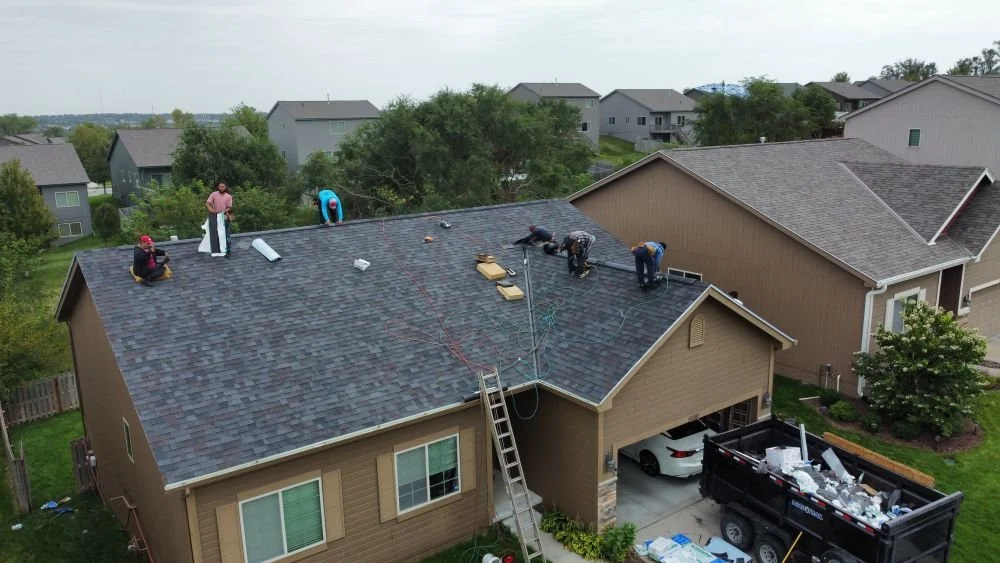 Roofing crew completing a roof replacement in Omaha NE with new shingles nearly finished