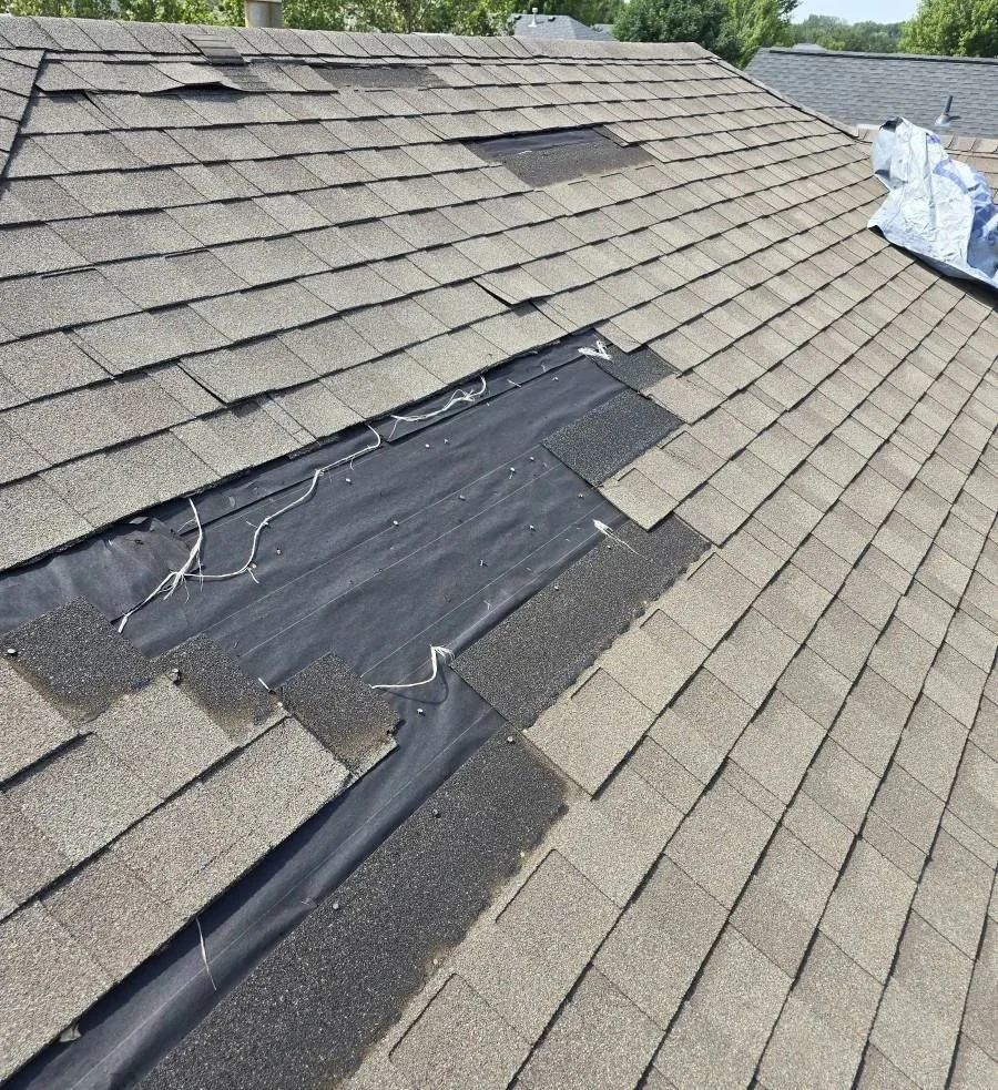 Close up of missing shingles on an Omaha roof showing exposed felt underlayment