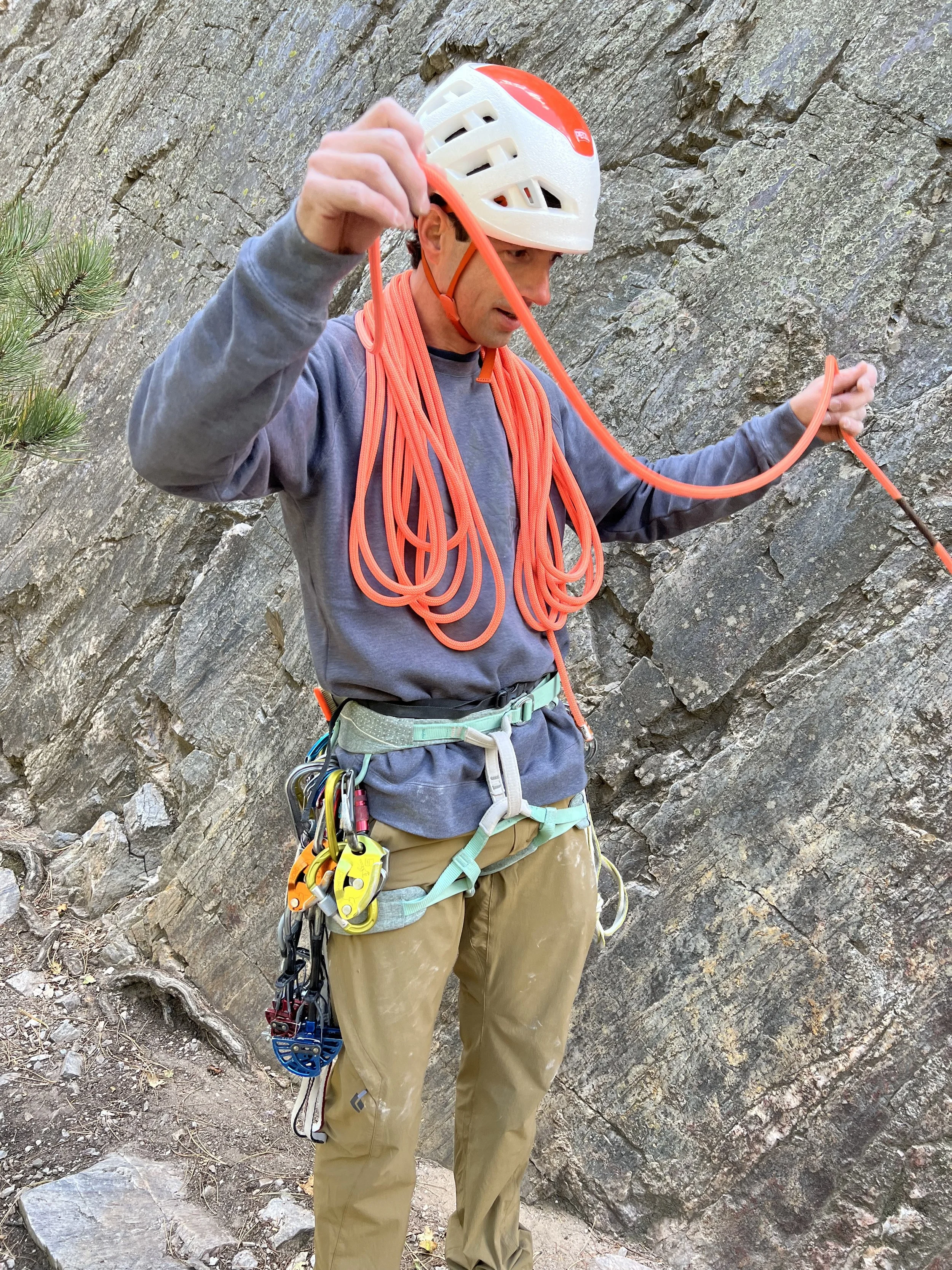 Experienced climbing guide organizing rope and technical equipment at an outdoor crag near Boulder