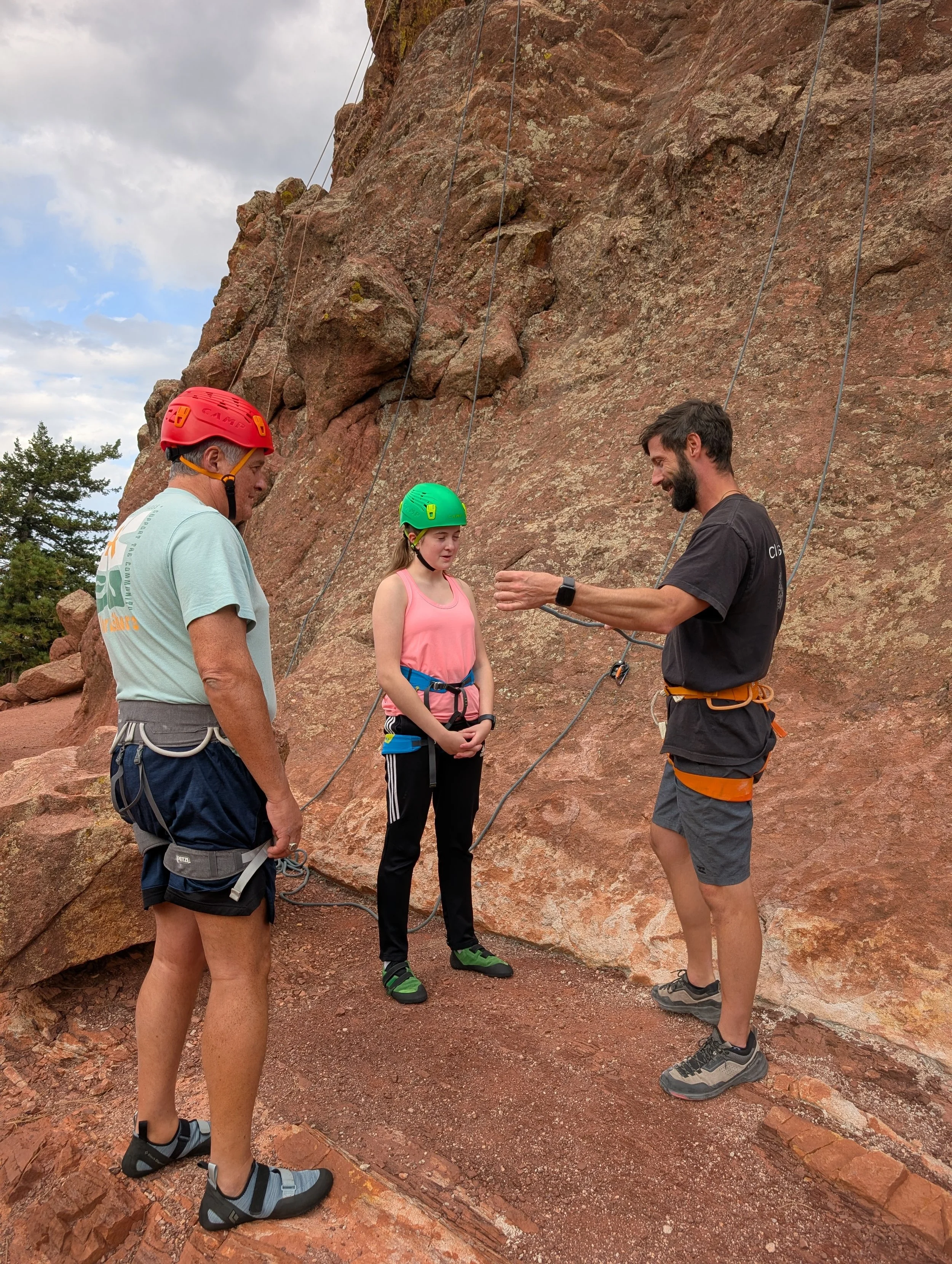 Guide briefing two beginner climbers before an outdoor climbing session near Boulder