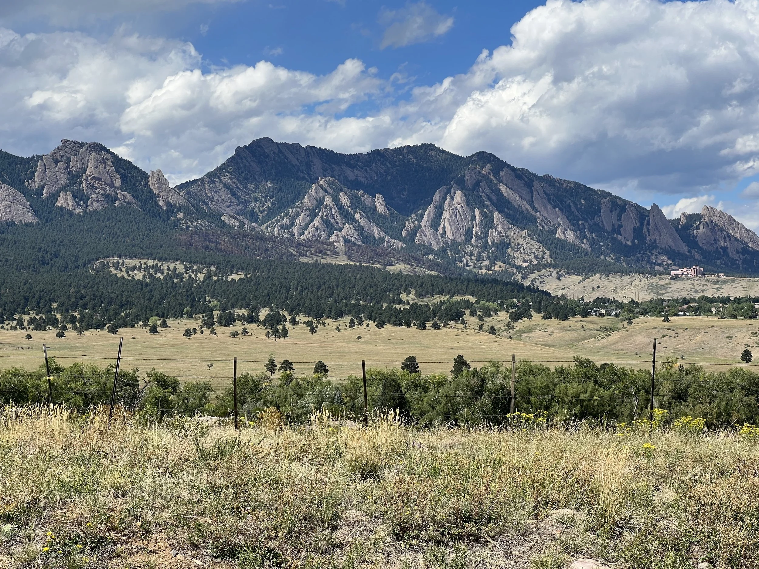 The numbered Flatirons rising above Boulder beneath large summer clouds