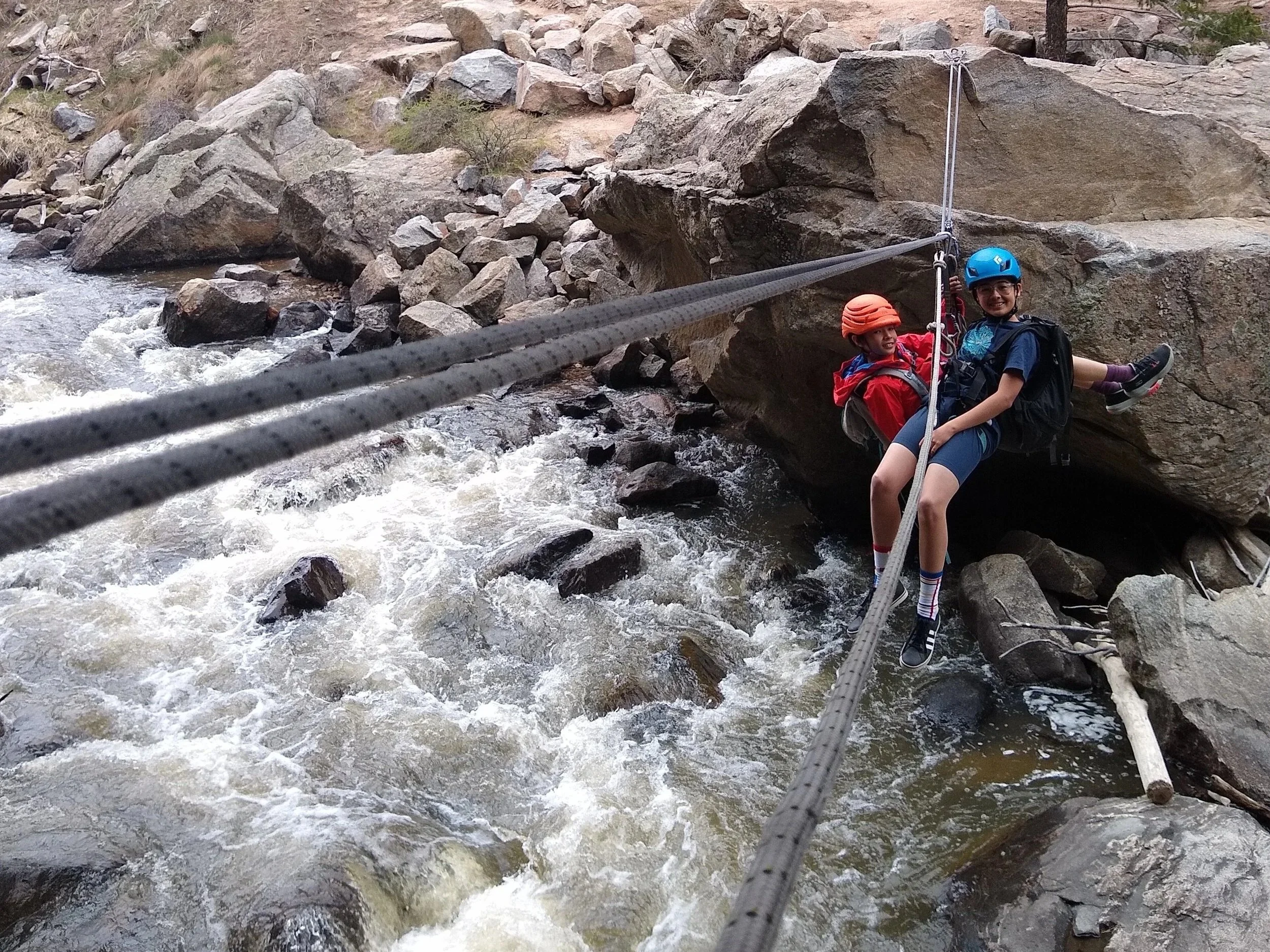 Climbers crossing Boulder Creek on a Tyrolean traverse