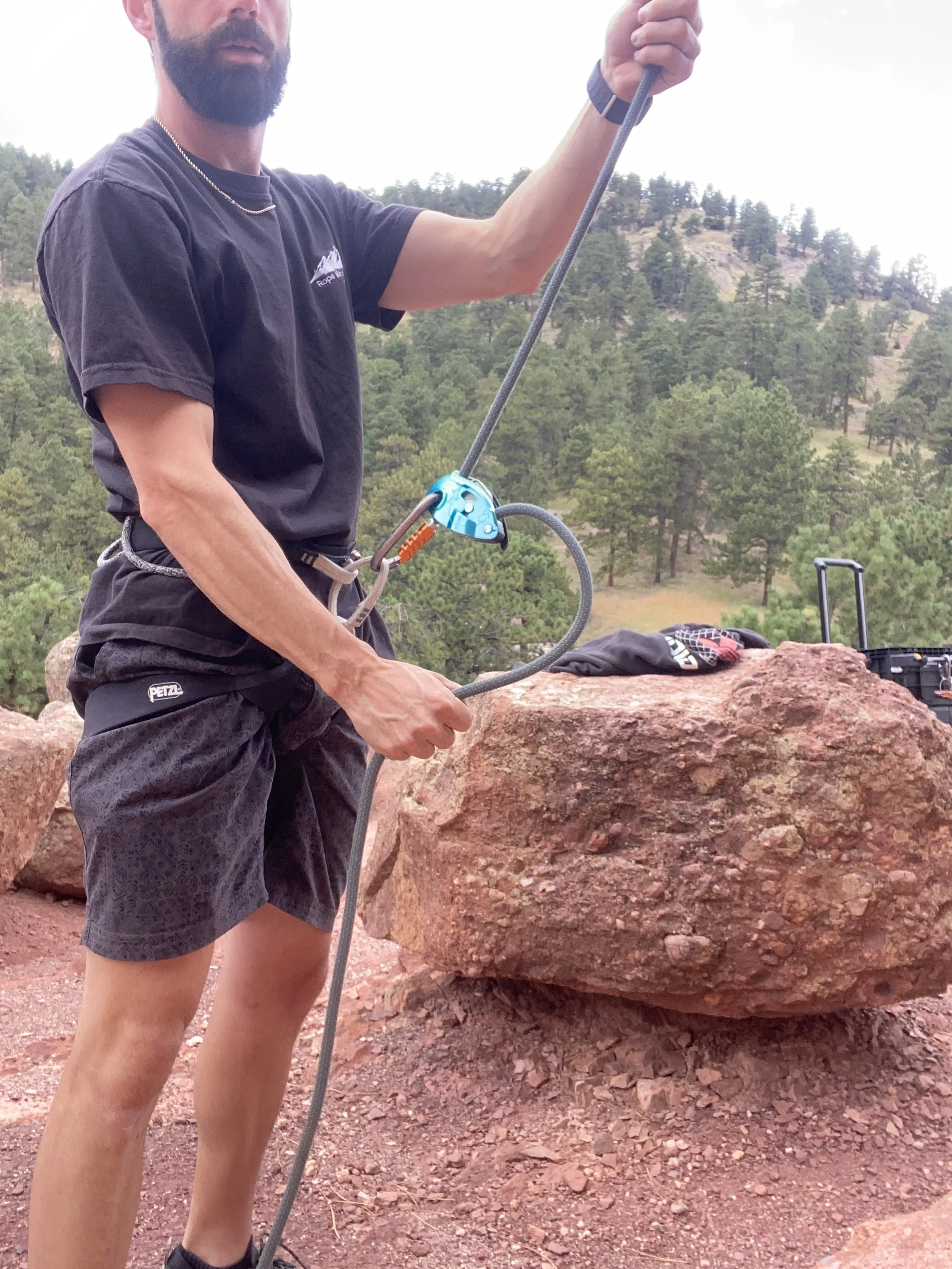Outdoor climbing instructor demonstrating a belay device and rope system