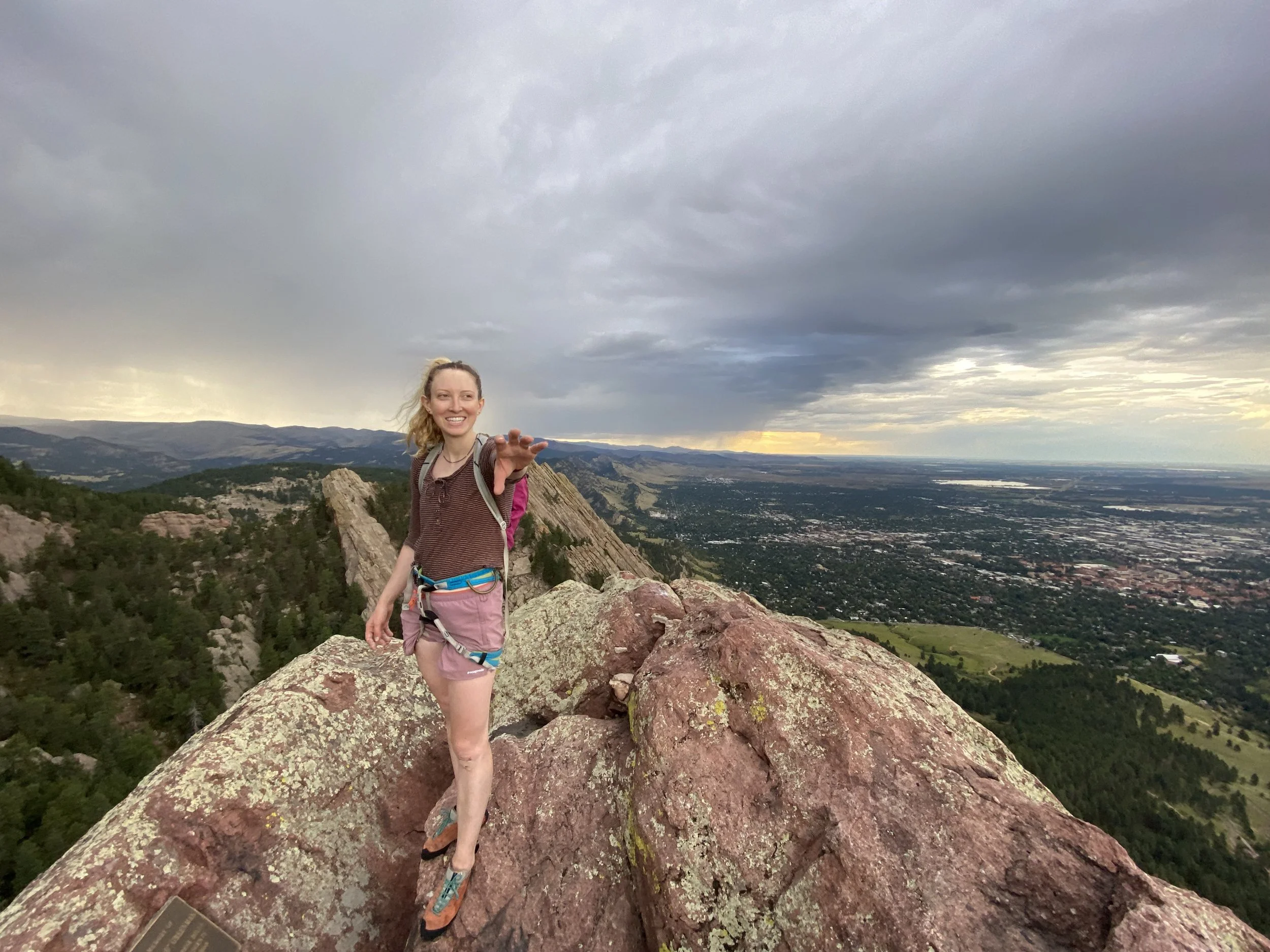 Climber standing on a Flatiron summit with Boulder and the plains spread below
