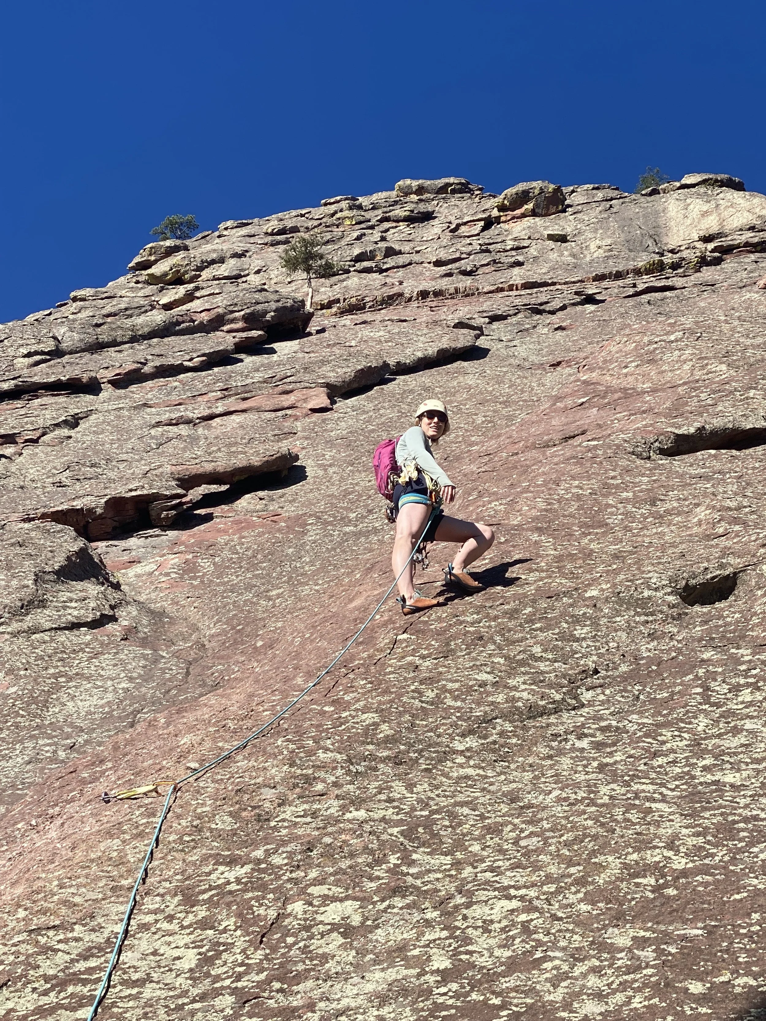 Climber moving up a broad sandstone slab on the First Flatiron