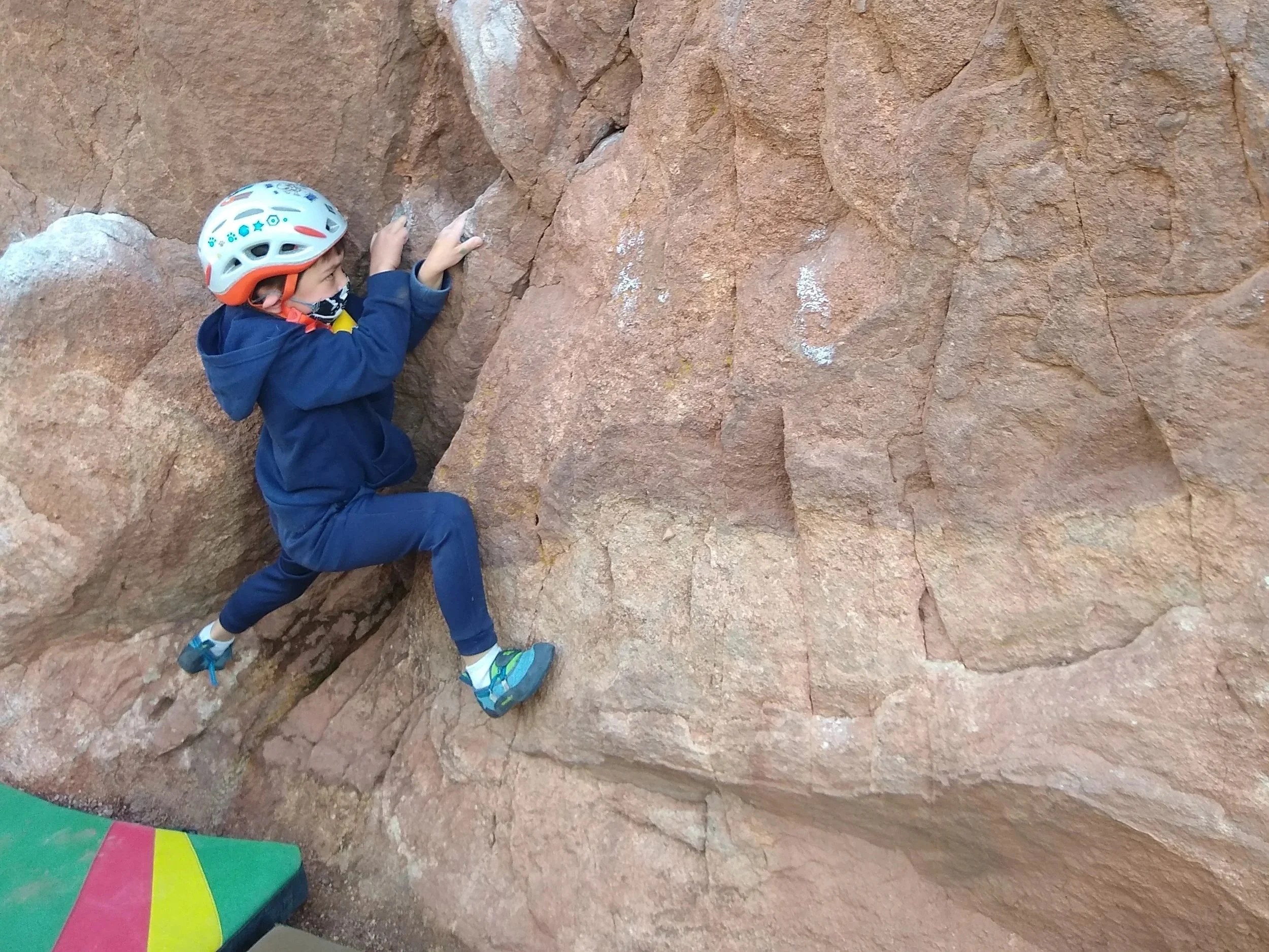 Young climber practicing movement on a Flagstaff sandstone boulder above a crash pad
