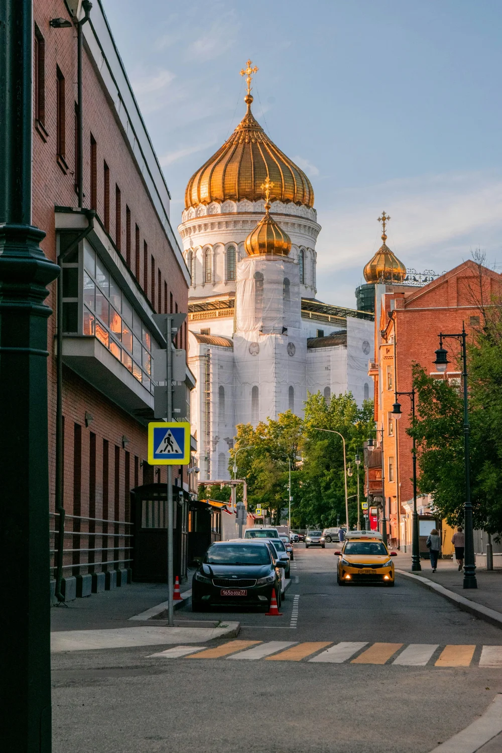A city street leading to a cathedral with golden domes