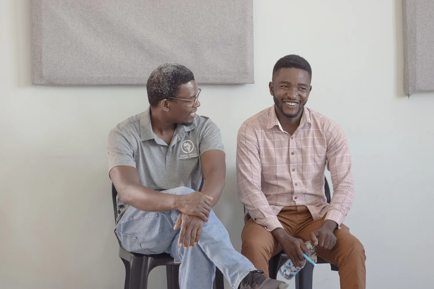 Two pastors seated side by side, laughing together