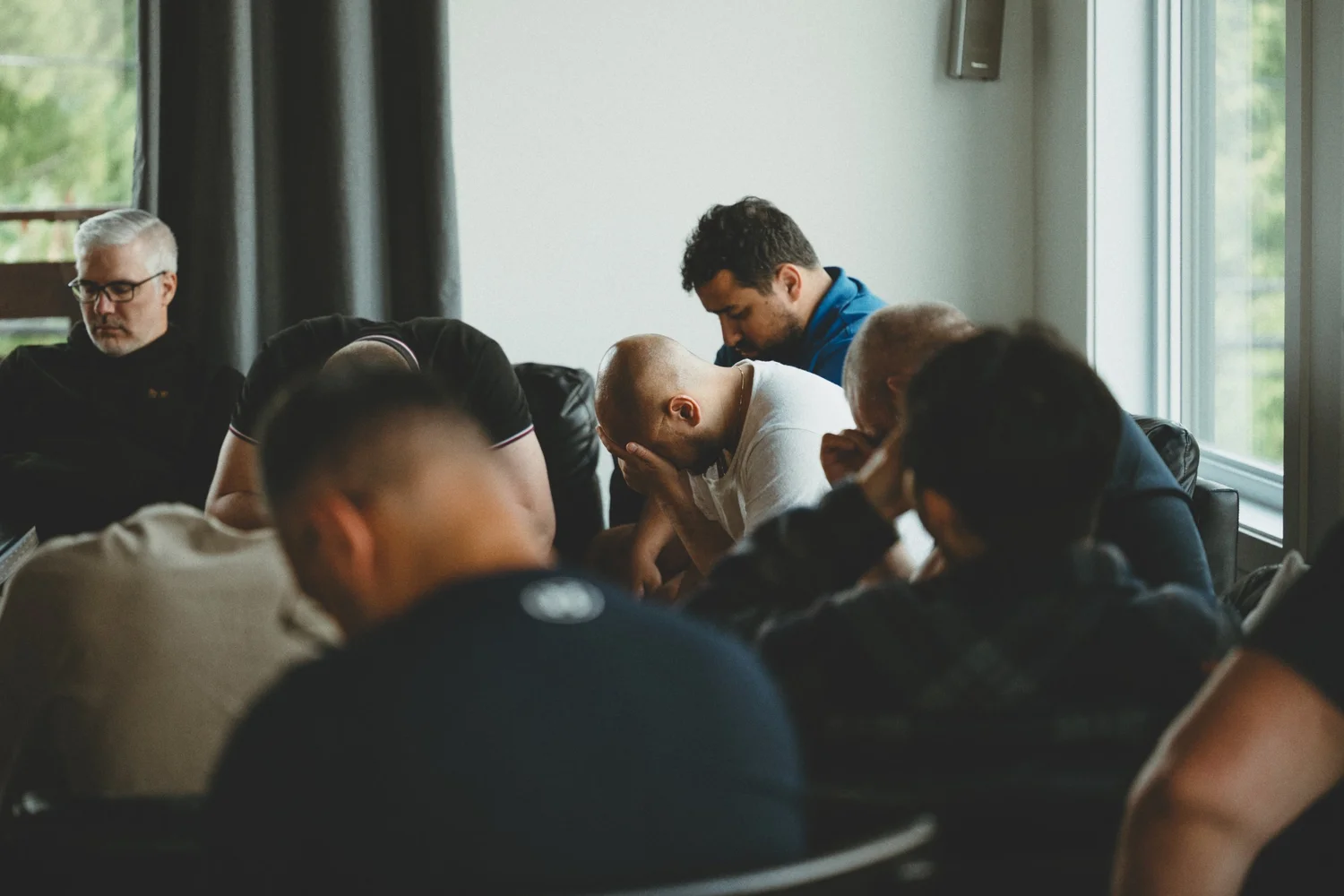 Men with heads bowed in prayer together