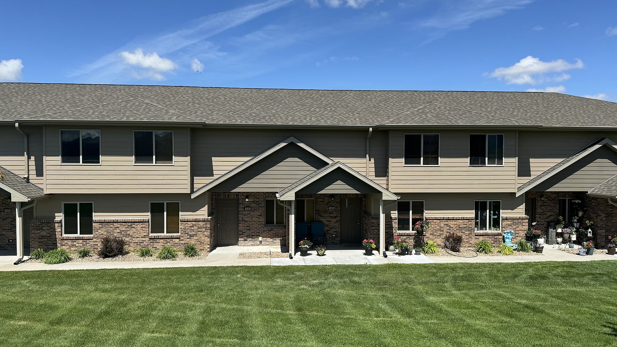 A row of Fountain Hills townhomes with gabled entries, stone bases and maintained lawns