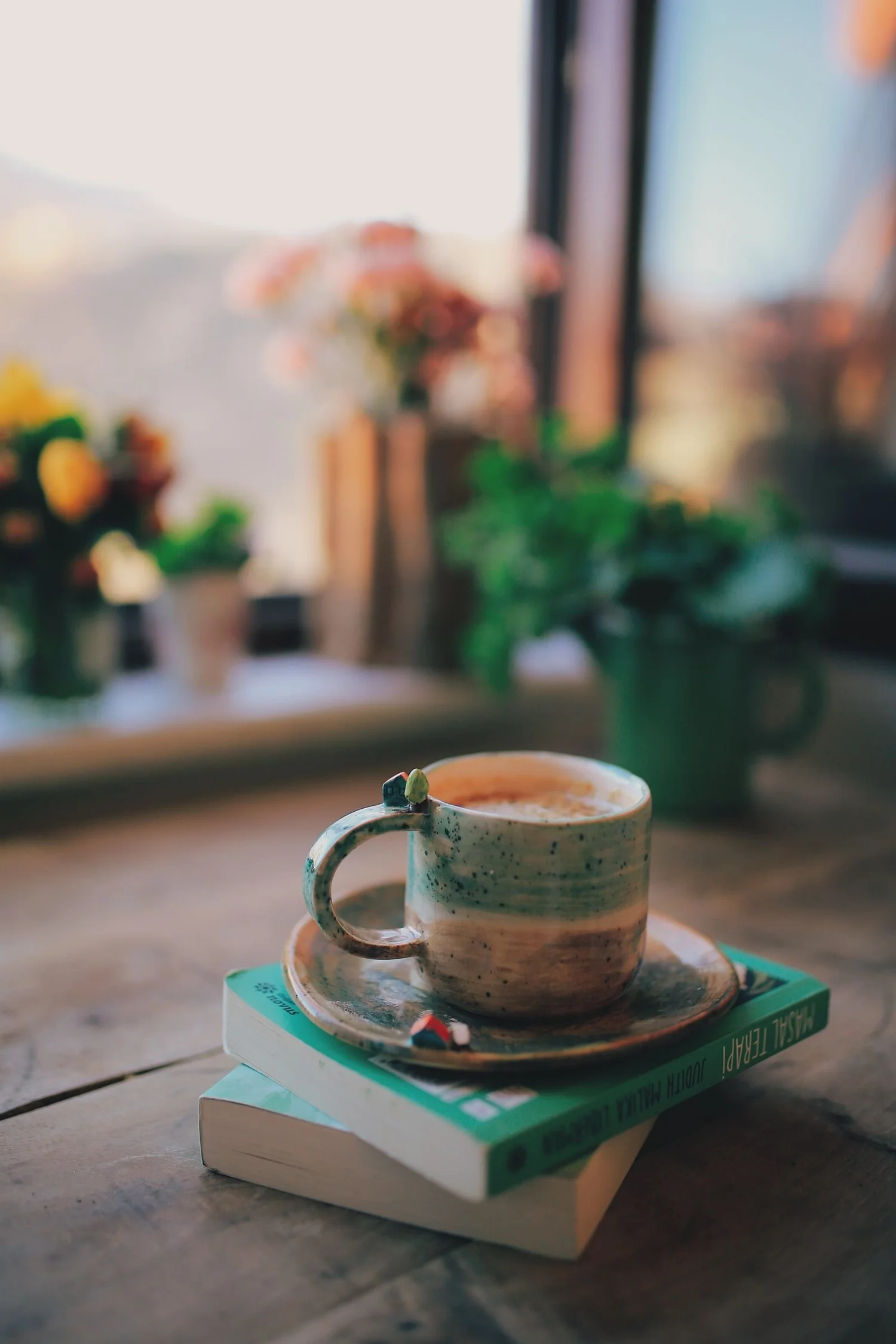 Coffee resting on a stack of books beside a window