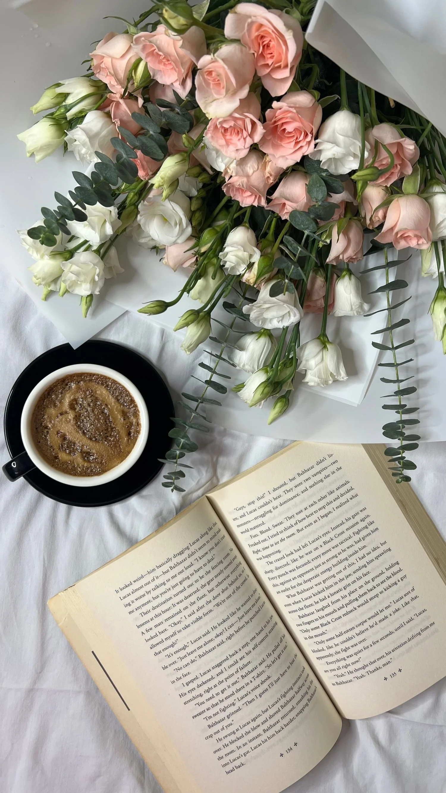 Coffee, an open book and pale roses in soft morning light