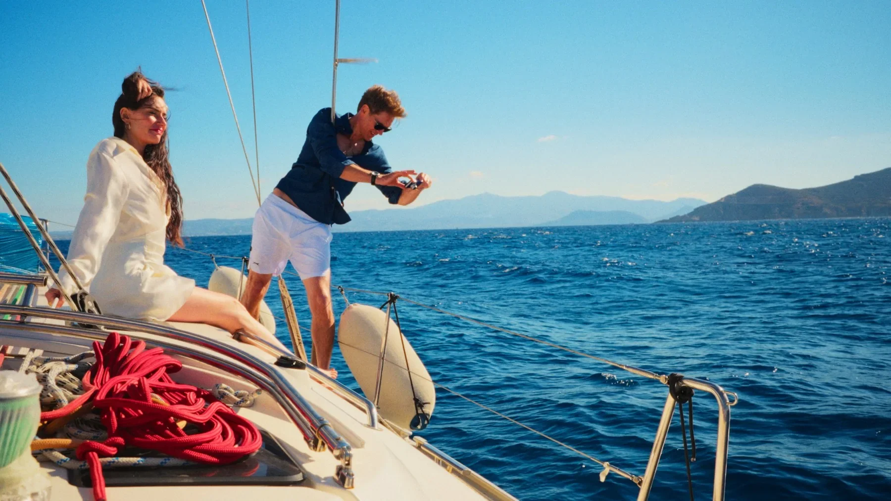 Two figures aboard a sailing boat in NAXOS.