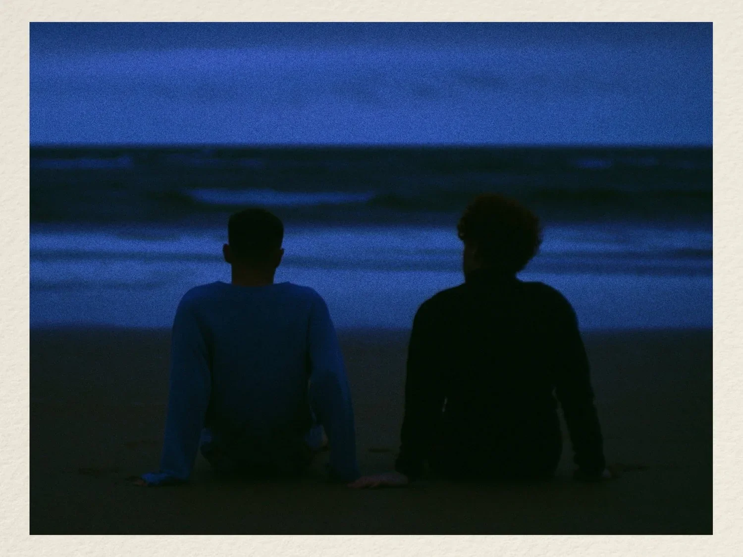 Two figures beside the sea.