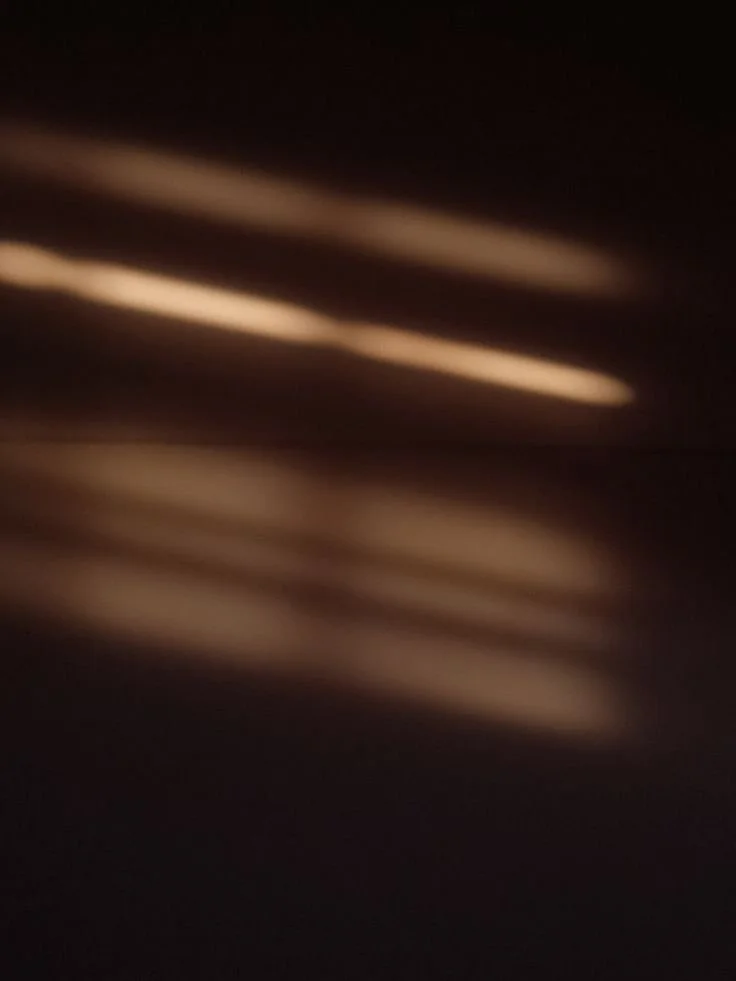 Soft bands of warm golden light falling across a dark surface, for BCLR's luxury packaging design service