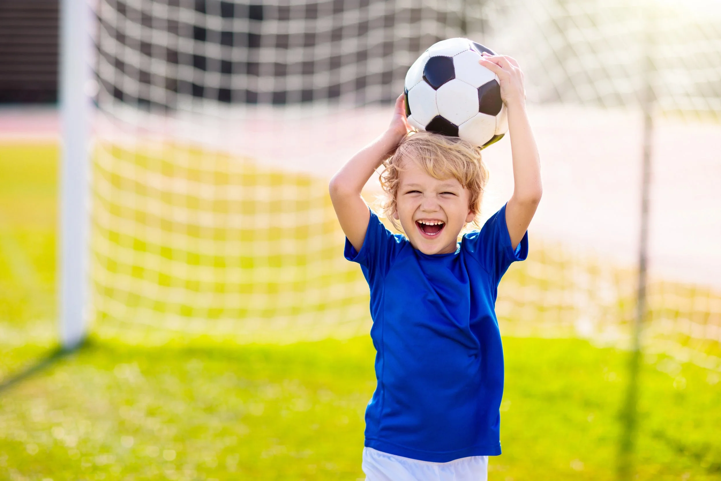 Young soccer player holding a ball above his head