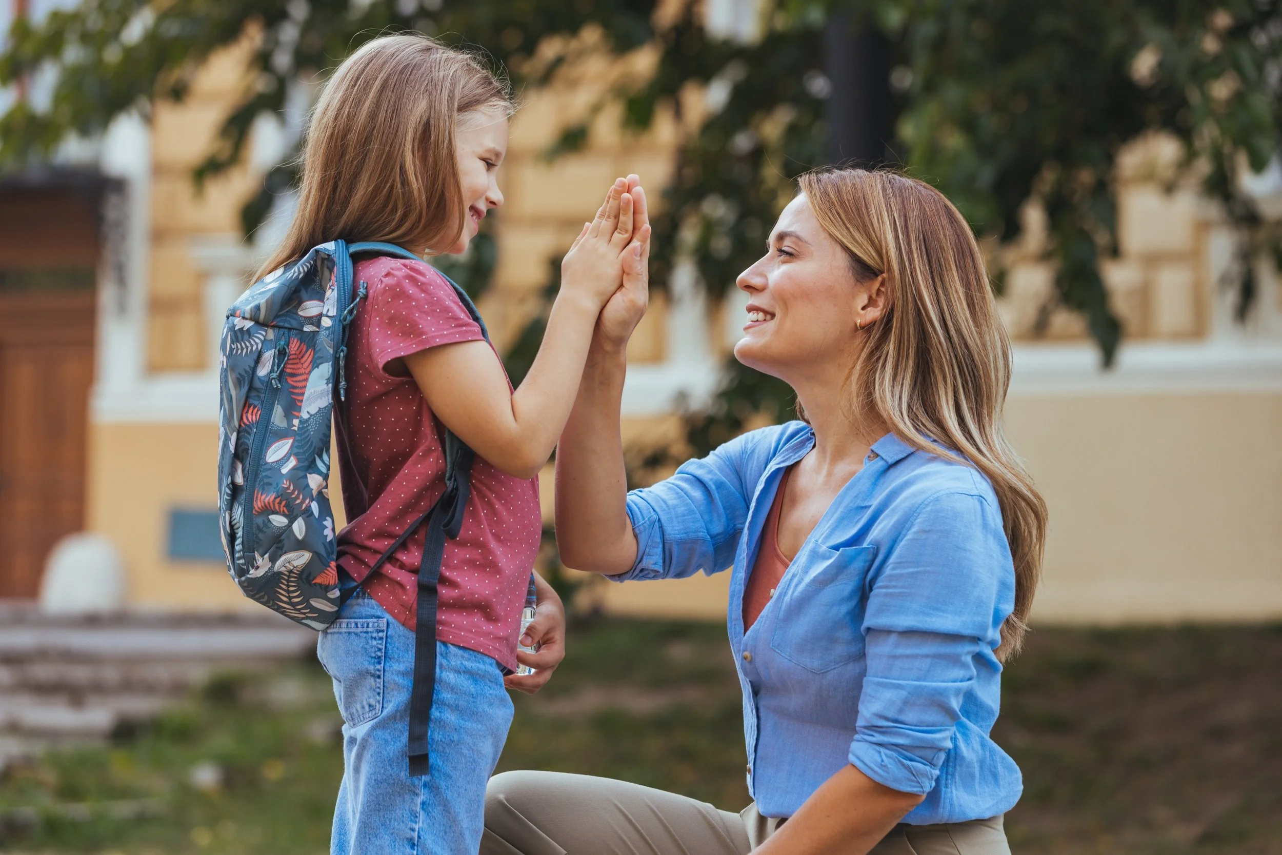 Parent and child sharing a high-five at school drop-off