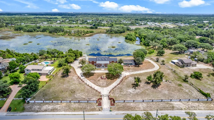 Aerial view of a colonial-style home beside a lake