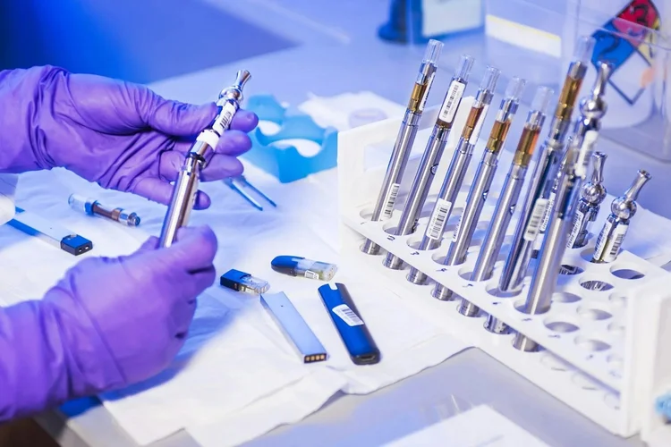 Someone wearing lab gloves working with metal capsules 