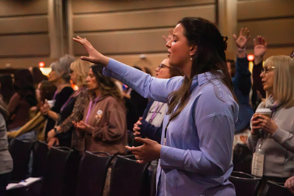 A woman worshipping among MORE attendees