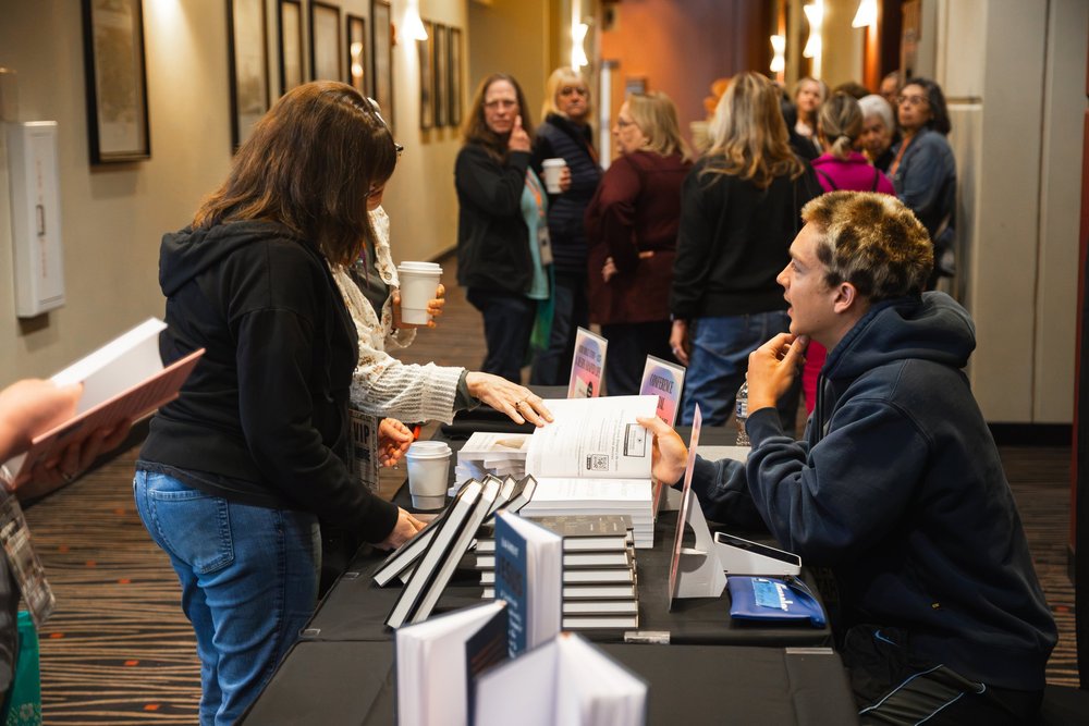 A guest talking with an exhibitor at a conference table