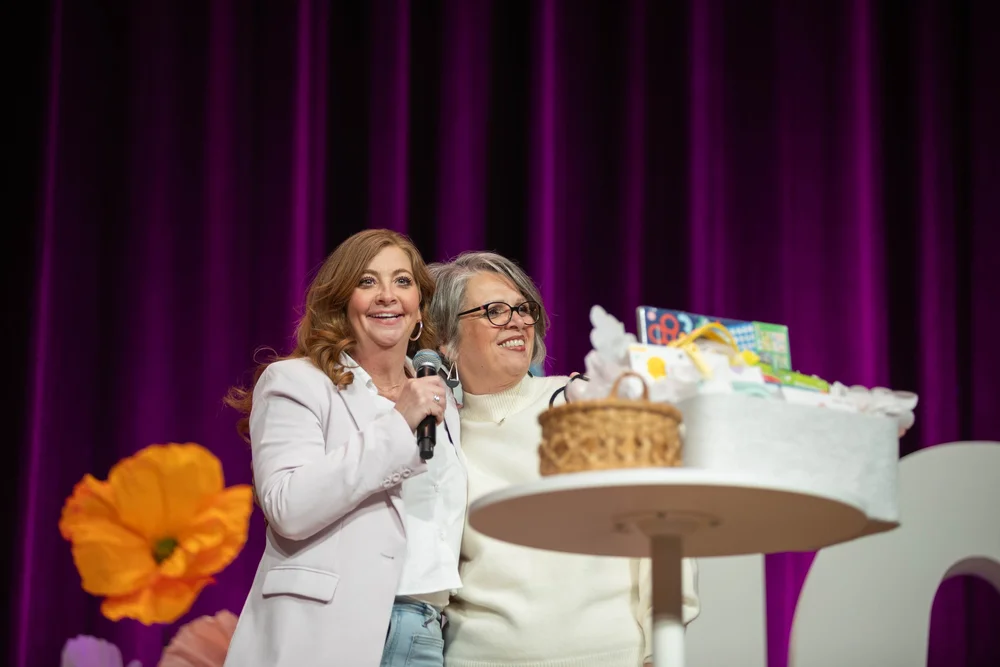 Two women celebrating a giveaway on the MORE 2025 stage