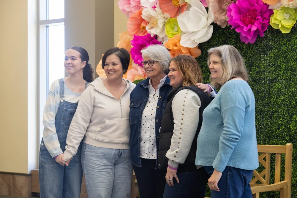 Friends posing together at the MORE 2025 flower wall