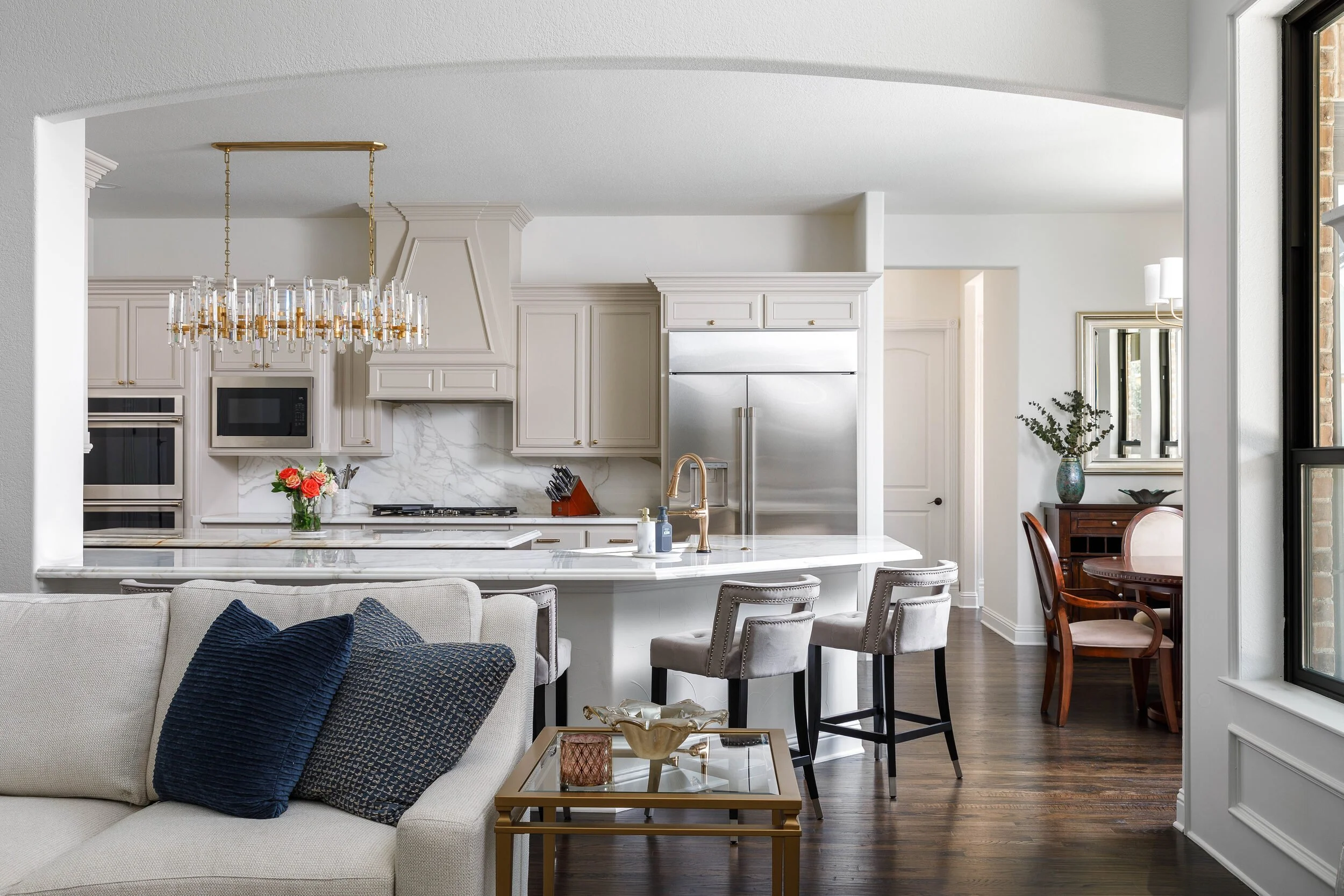 Kitchen and breakfast area with a crystal chandelier, cream cabinetry and a marble-topped island