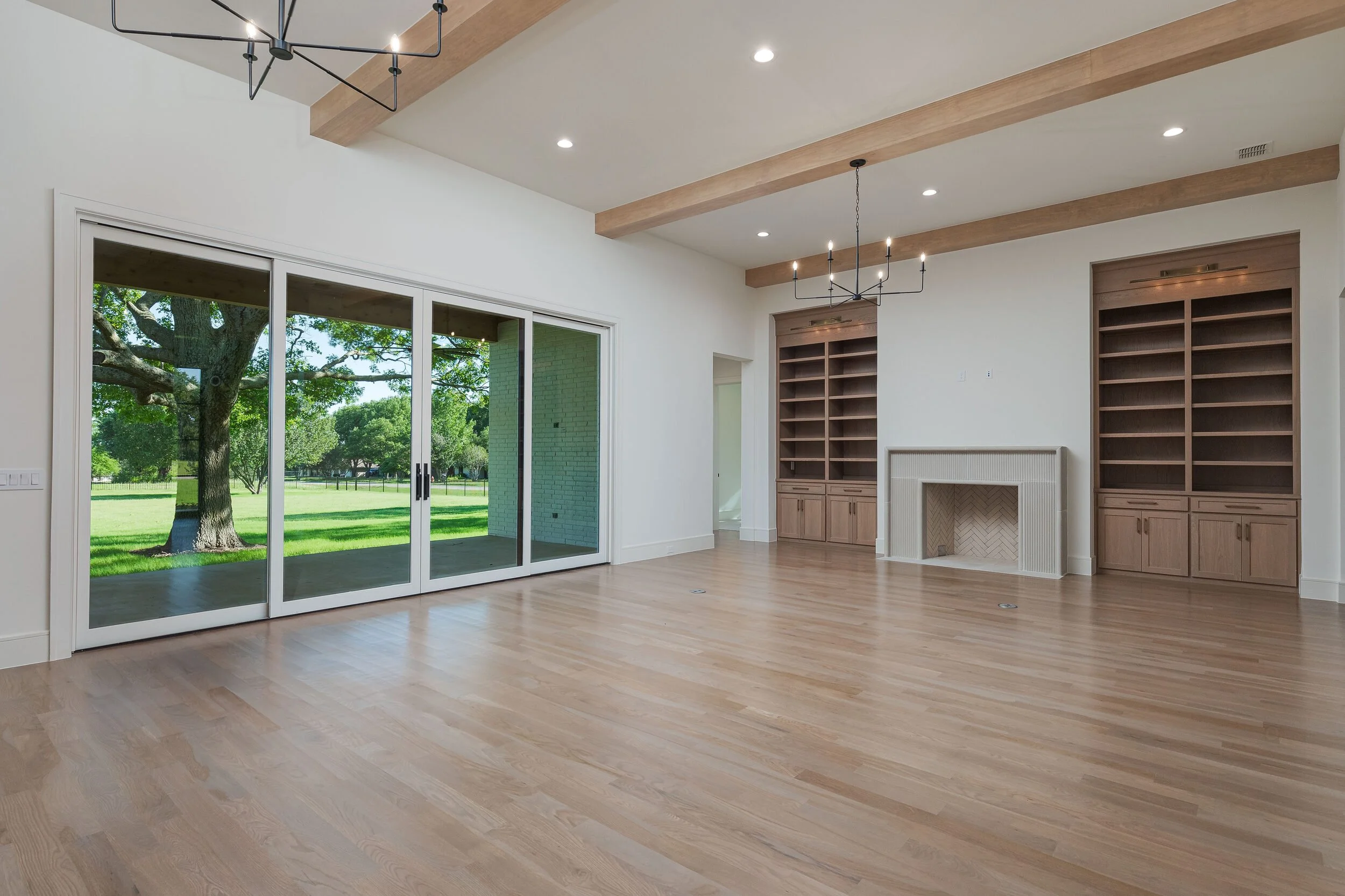Great room with exposed beams, a wall of sliding glass doors and white oak floors