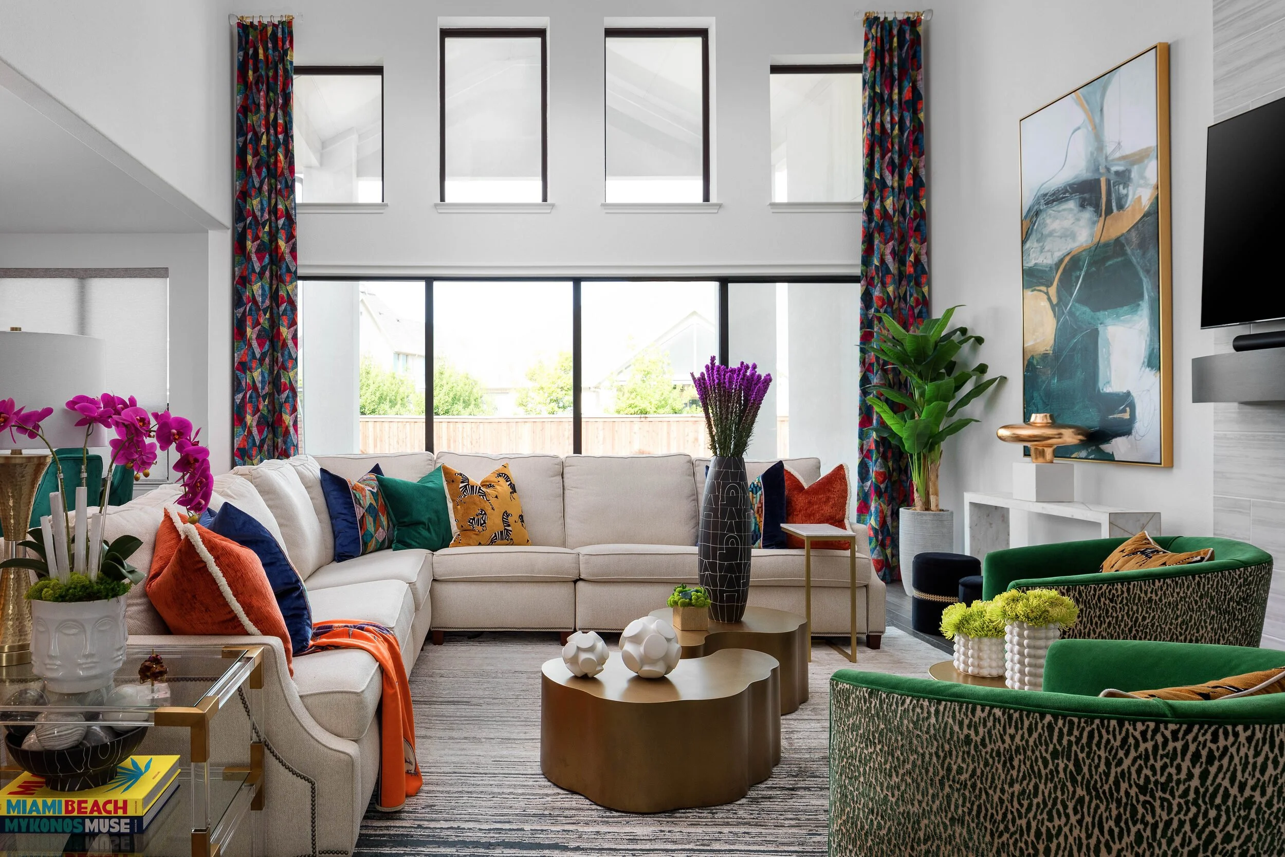 Living room with a cream sectional, green velvet chairs and a sculptural bronze coffee table, designed by Amy Switzer Design in Prosper, Texas