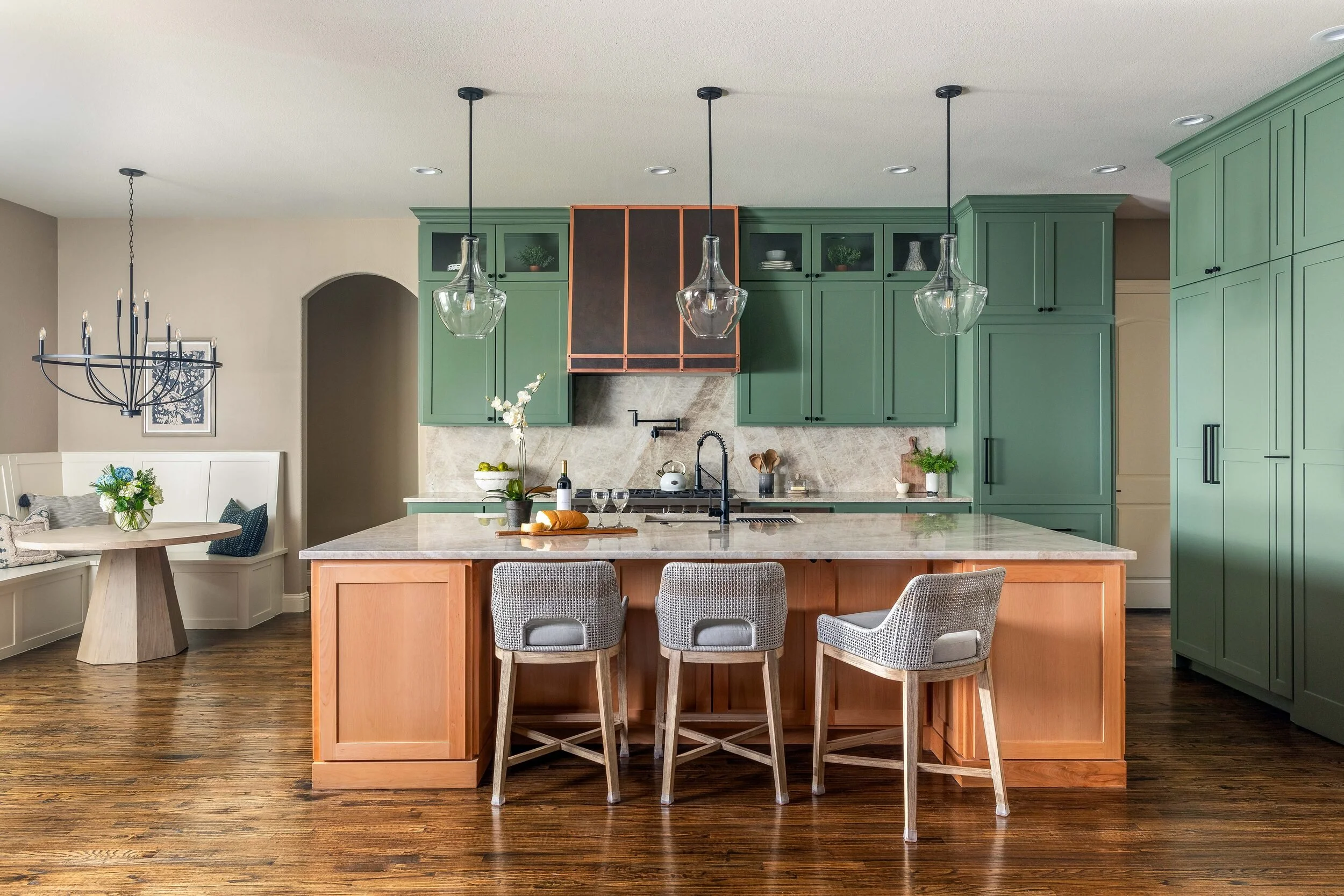 Kitchen with sage green cabinetry, a copper-trimmed range hood and a warm wood island, designed by Ashley Pate Interior Design