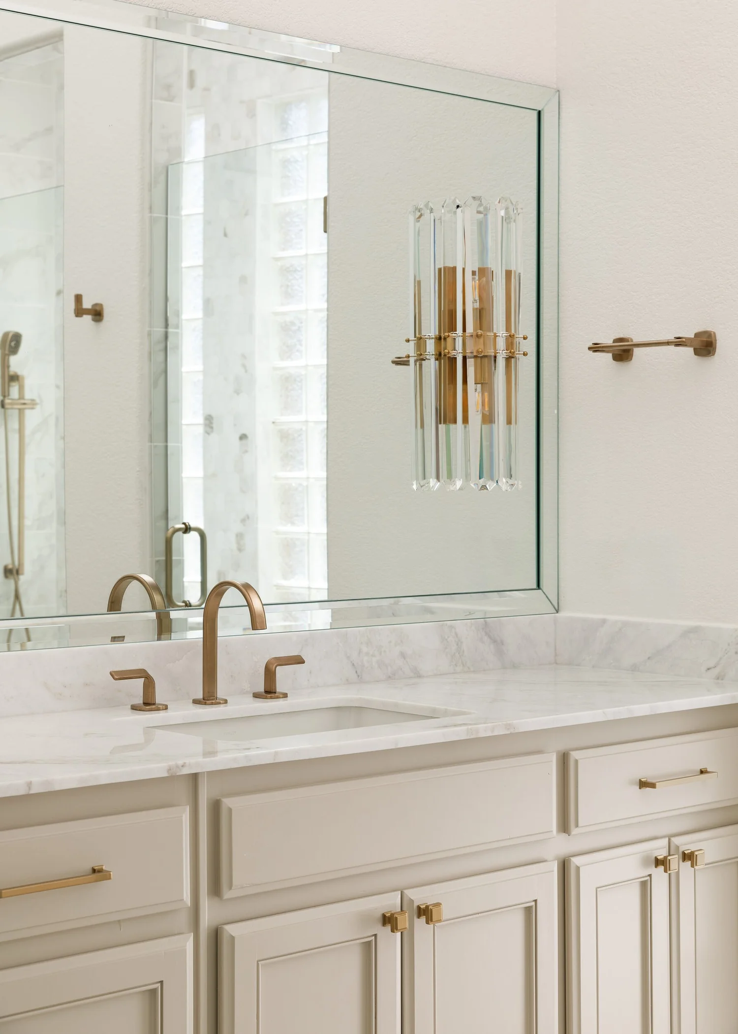Vanity detail with brass sconces, a framed mirror and marble countertop