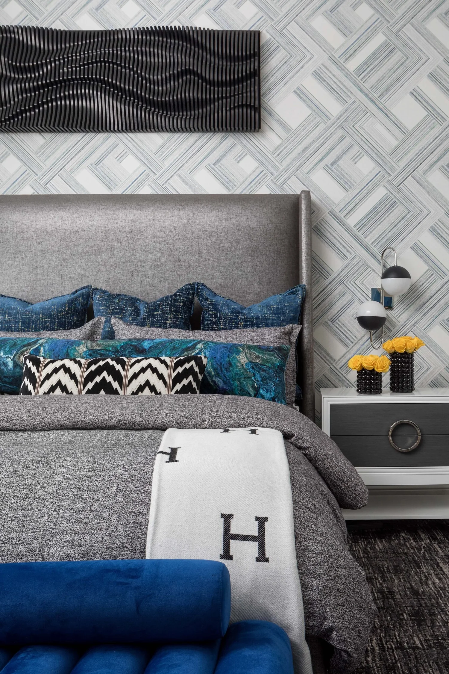 Detail of layered bedding, chevron pillows and an upholstered headboard