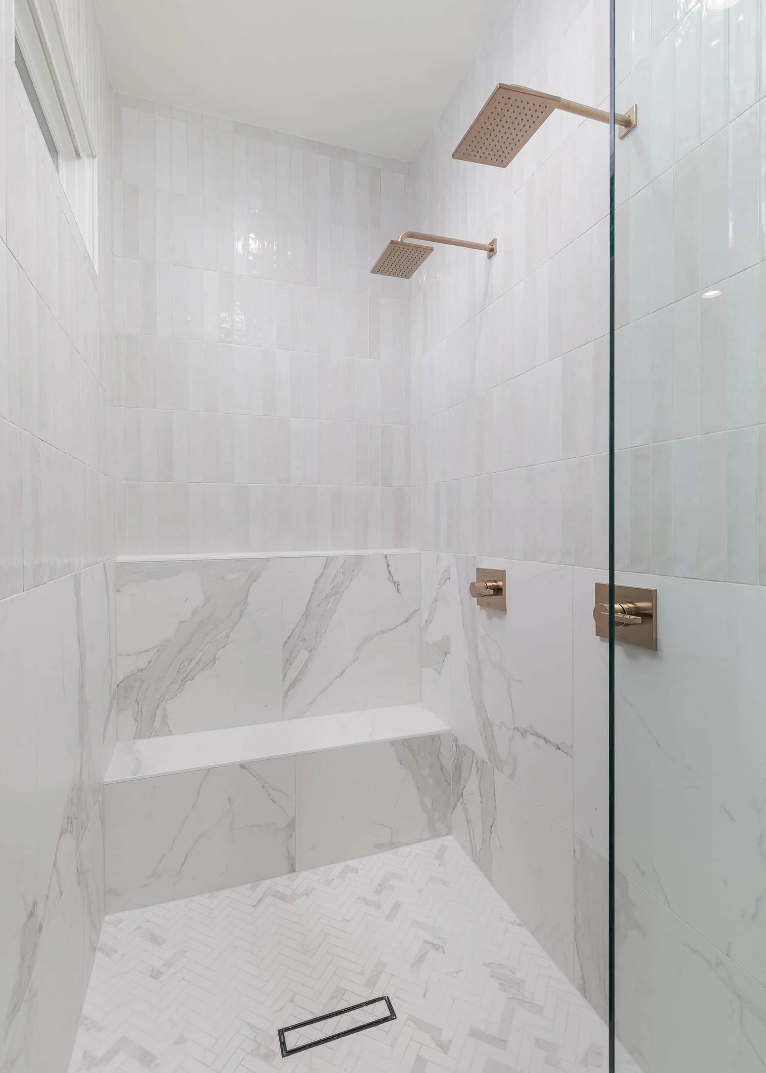 Marble shower with a built-in bench and brass fixtures