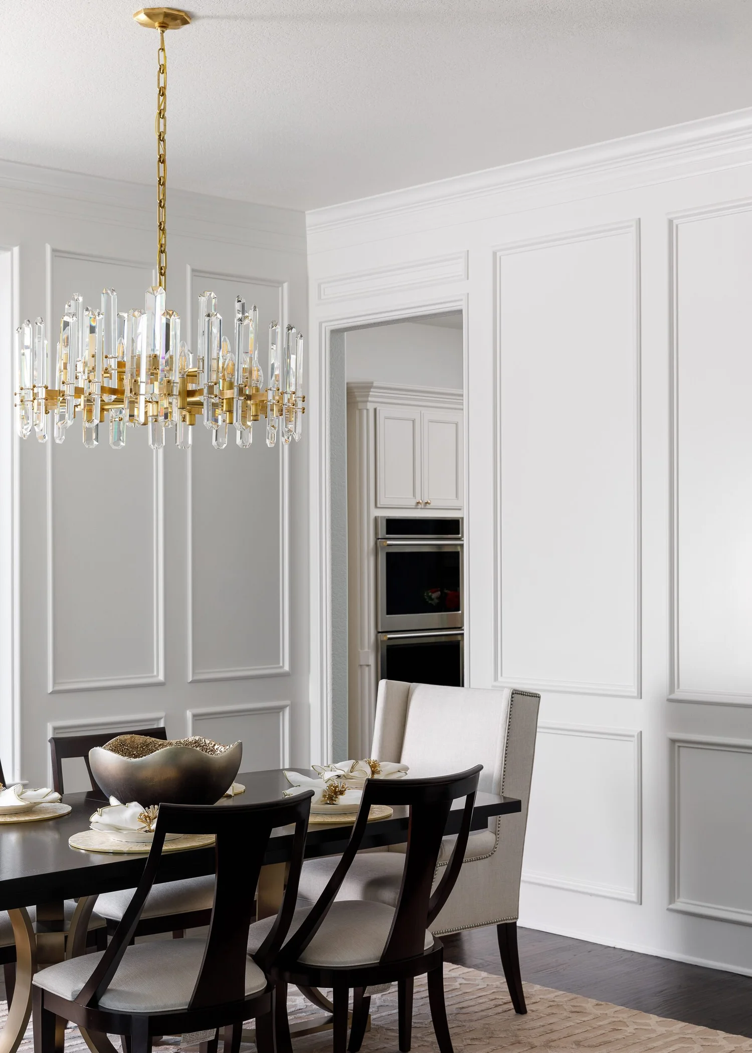 Dining table detail with a crystal chandelier and paneled walls