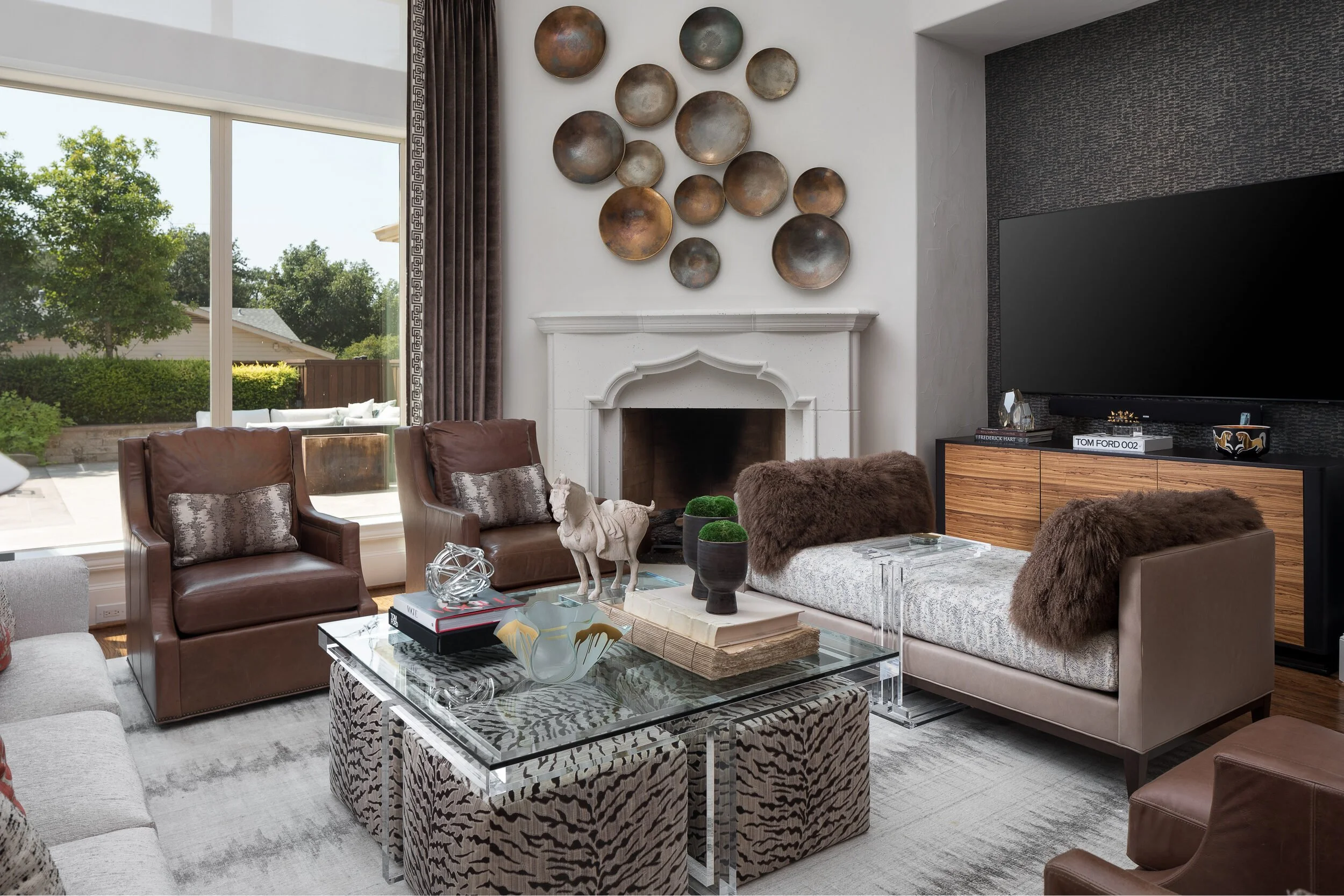 Fireplace wall with bronze plate arrangement, leather chairs and a fur-draped chaise